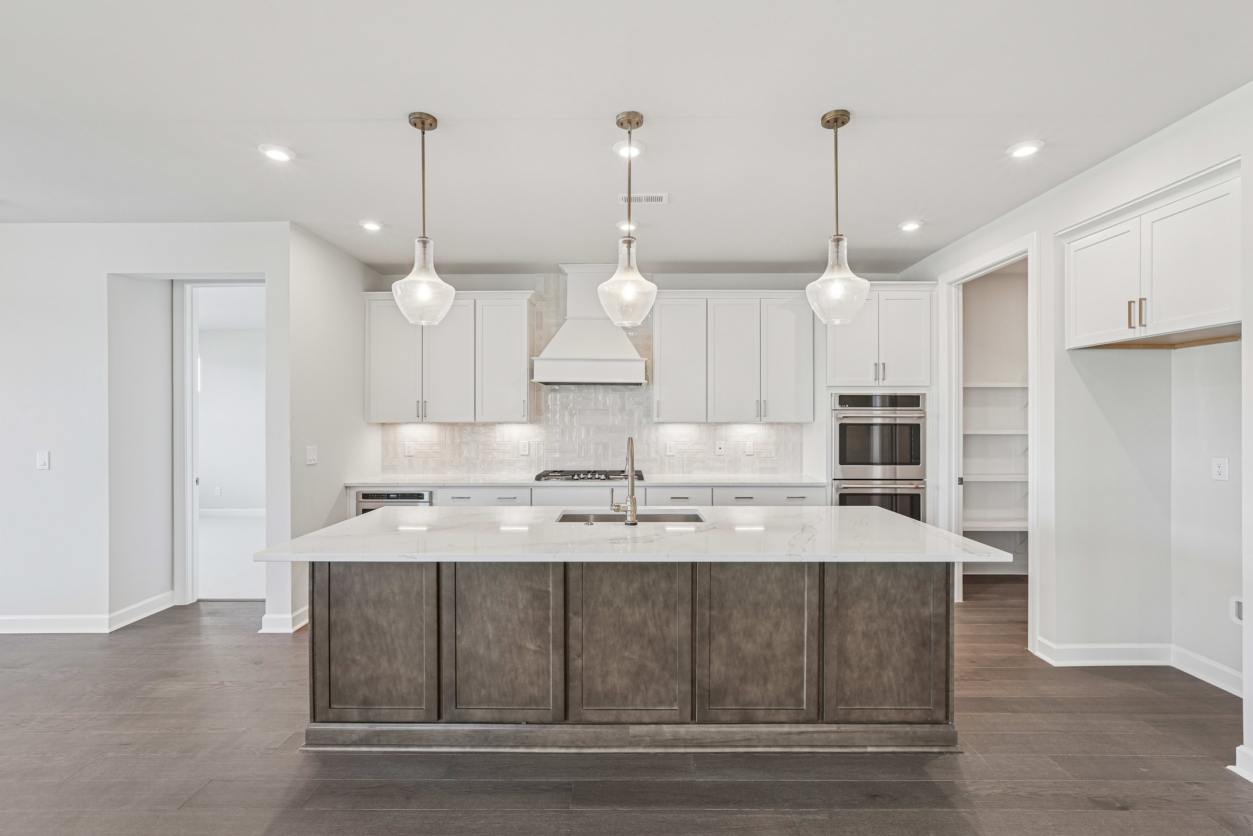 A modern, open-concept kitchen with a large island, white cabinets, and pendant lighting fixtures.