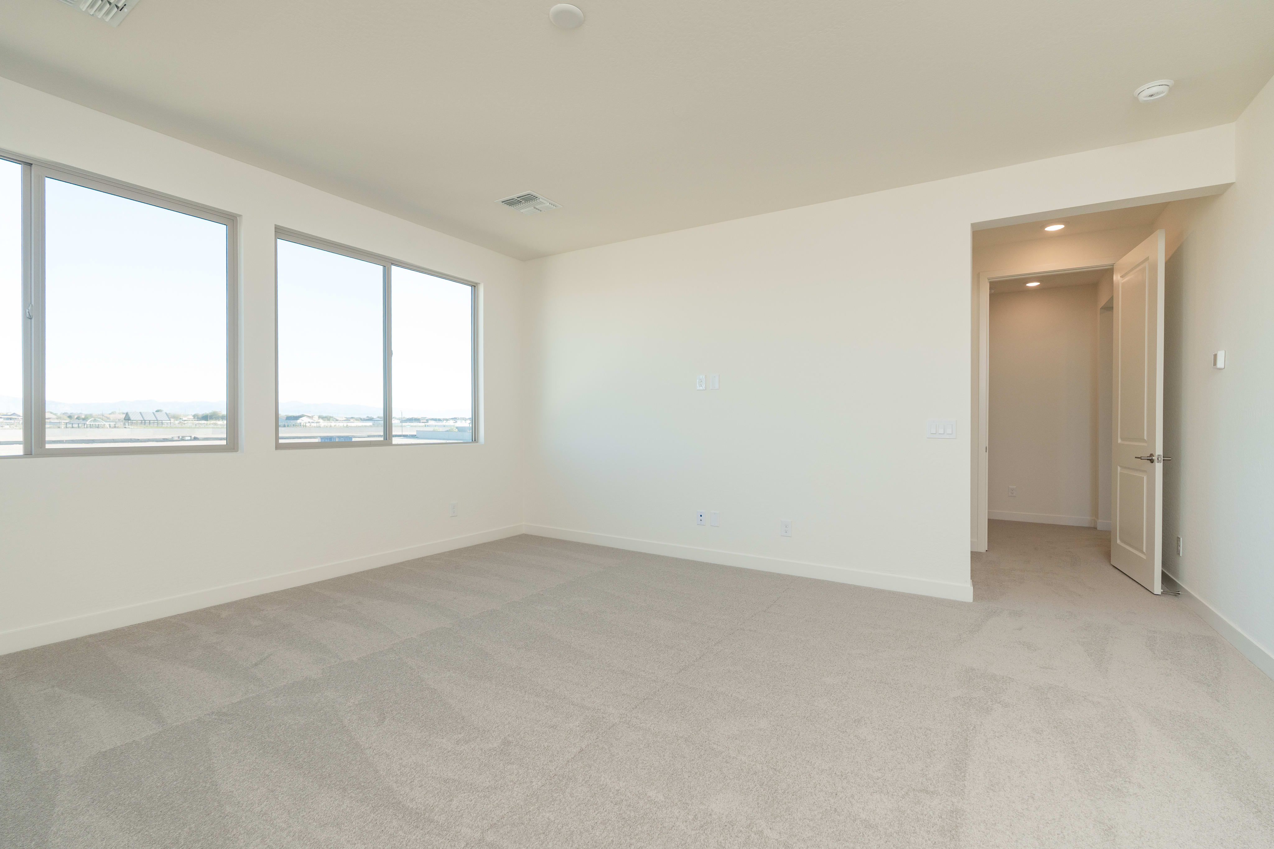 A spacious, well-lit room with large windows, a neutral color scheme, and a clean, minimalist design.