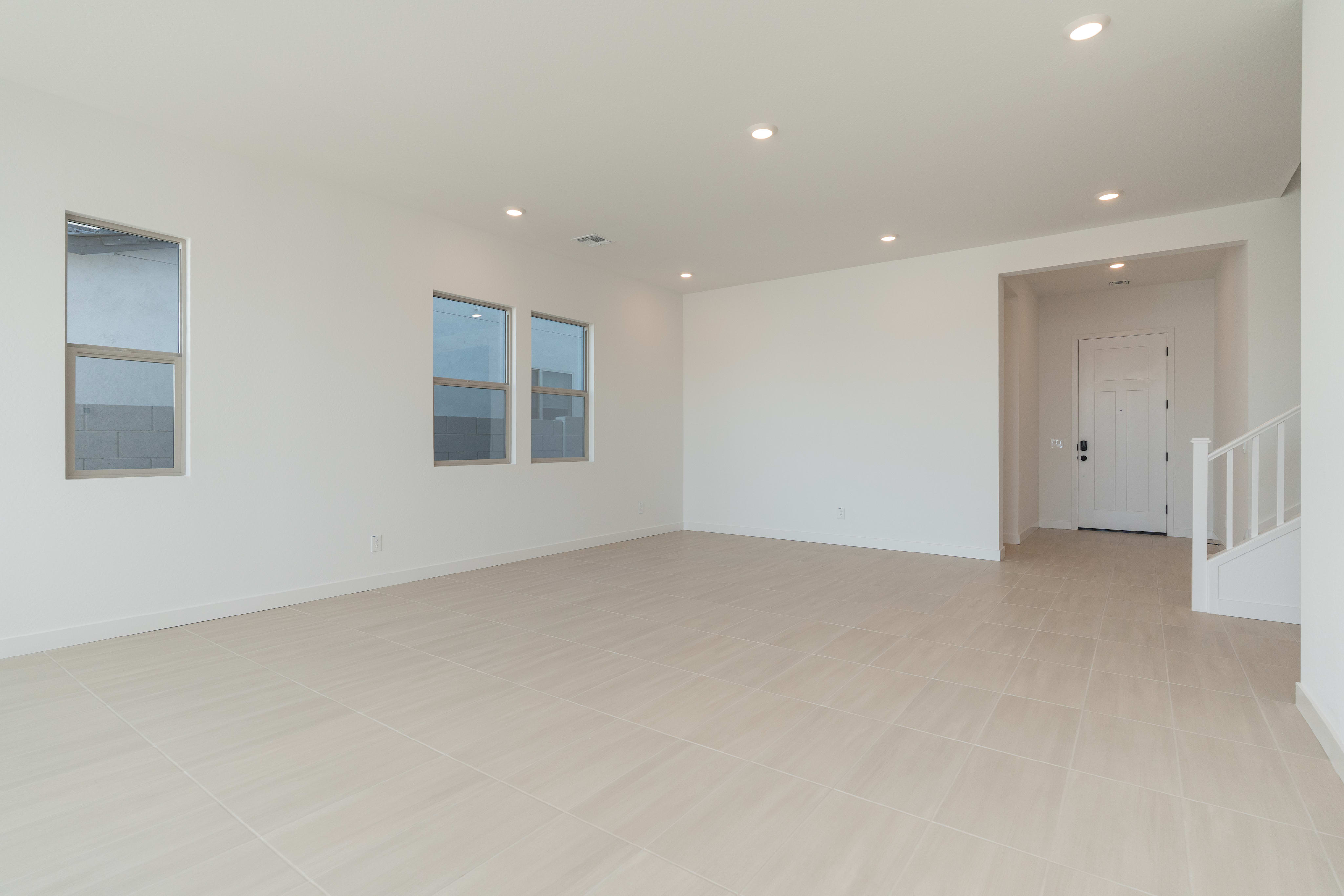 A spacious, minimalist room with white walls, hardwood floors, and recessed lighting, providing a clean and bright atmosphere.