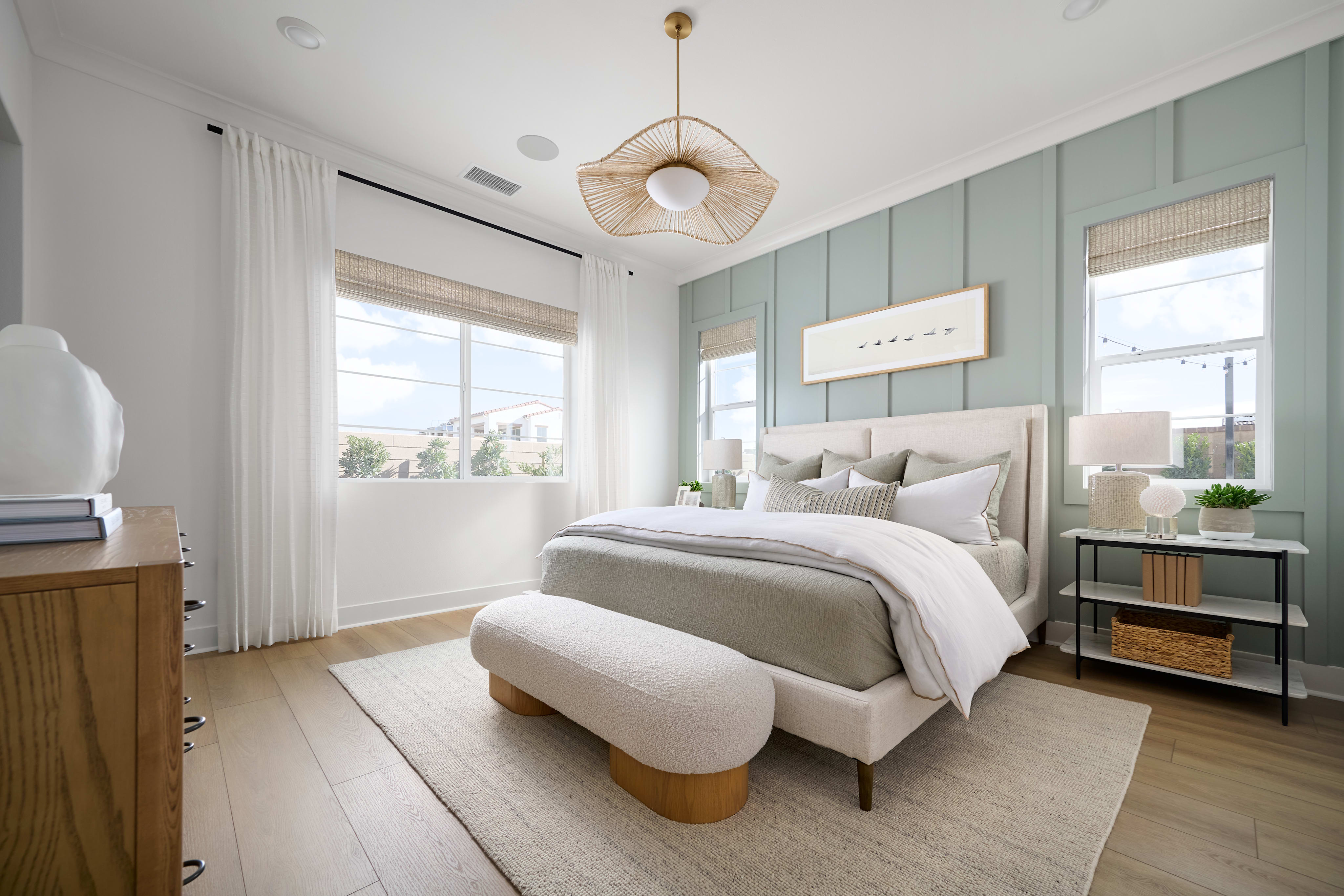 A cozy and inviting bedroom with a plush, neutral-toned bed, a woven pendant light, and a mix of natural and modern decor elements creating a serene and harmonious atmosphere.