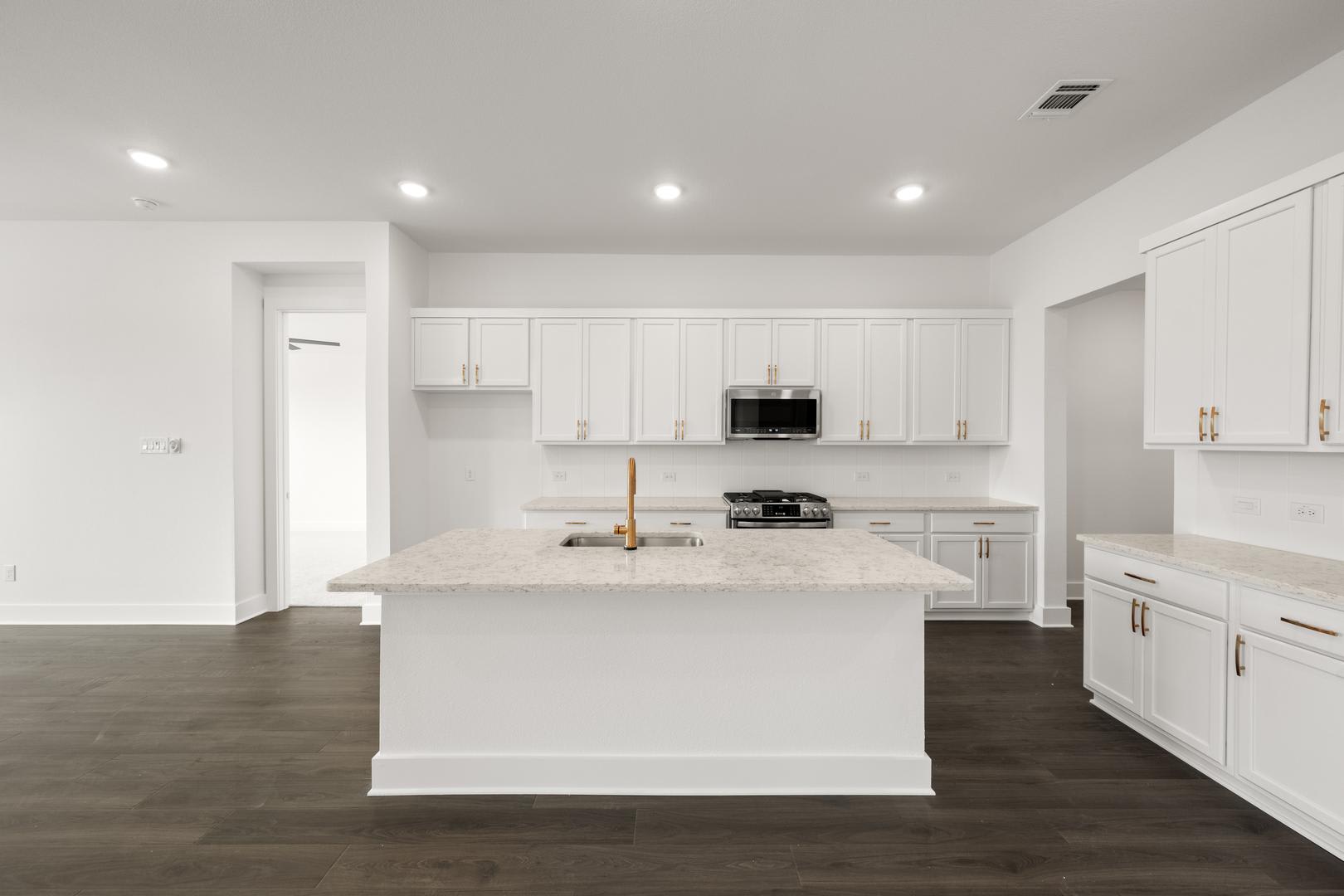 A modern, bright kitchen with white cabinets, a large island, and dark hardwood floors.