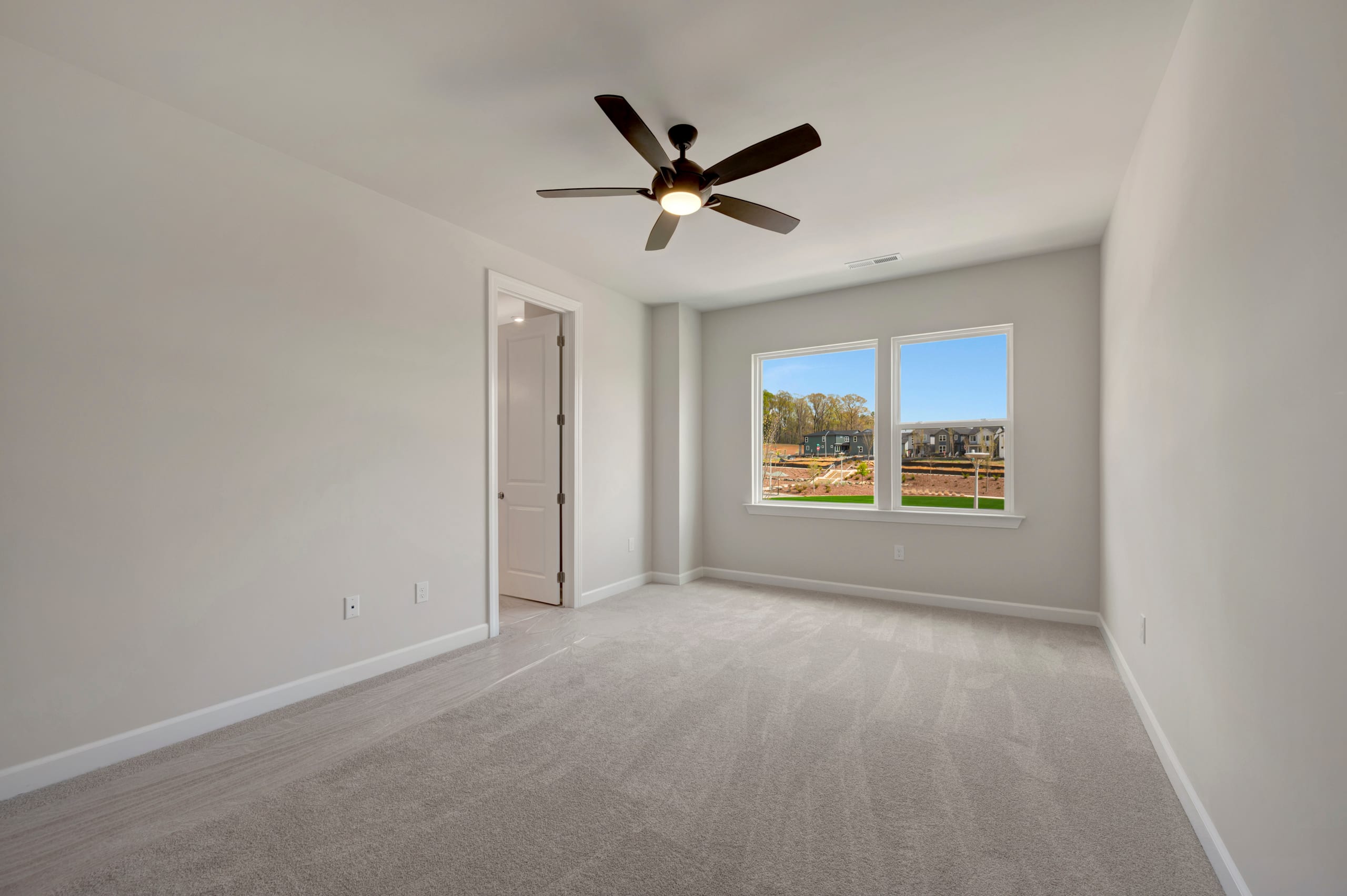 A spacious, well-lit room with a ceiling fan and a window overlooking a scenic outdoor area.