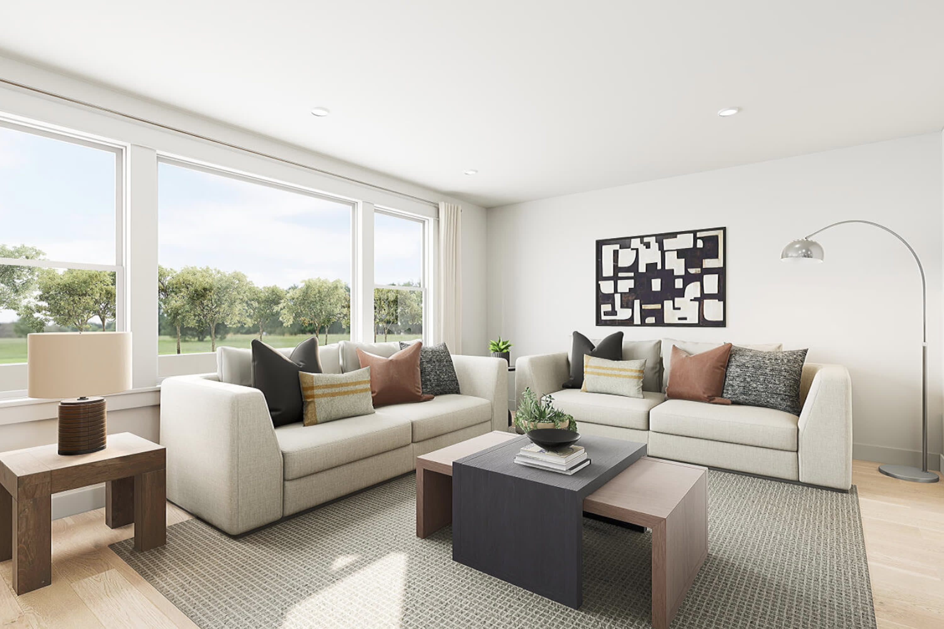 A modern and minimalist living room with large windows overlooking a grassy outdoor area, featuring a white sofa, wooden coffee table, and a decorative wall art piece.