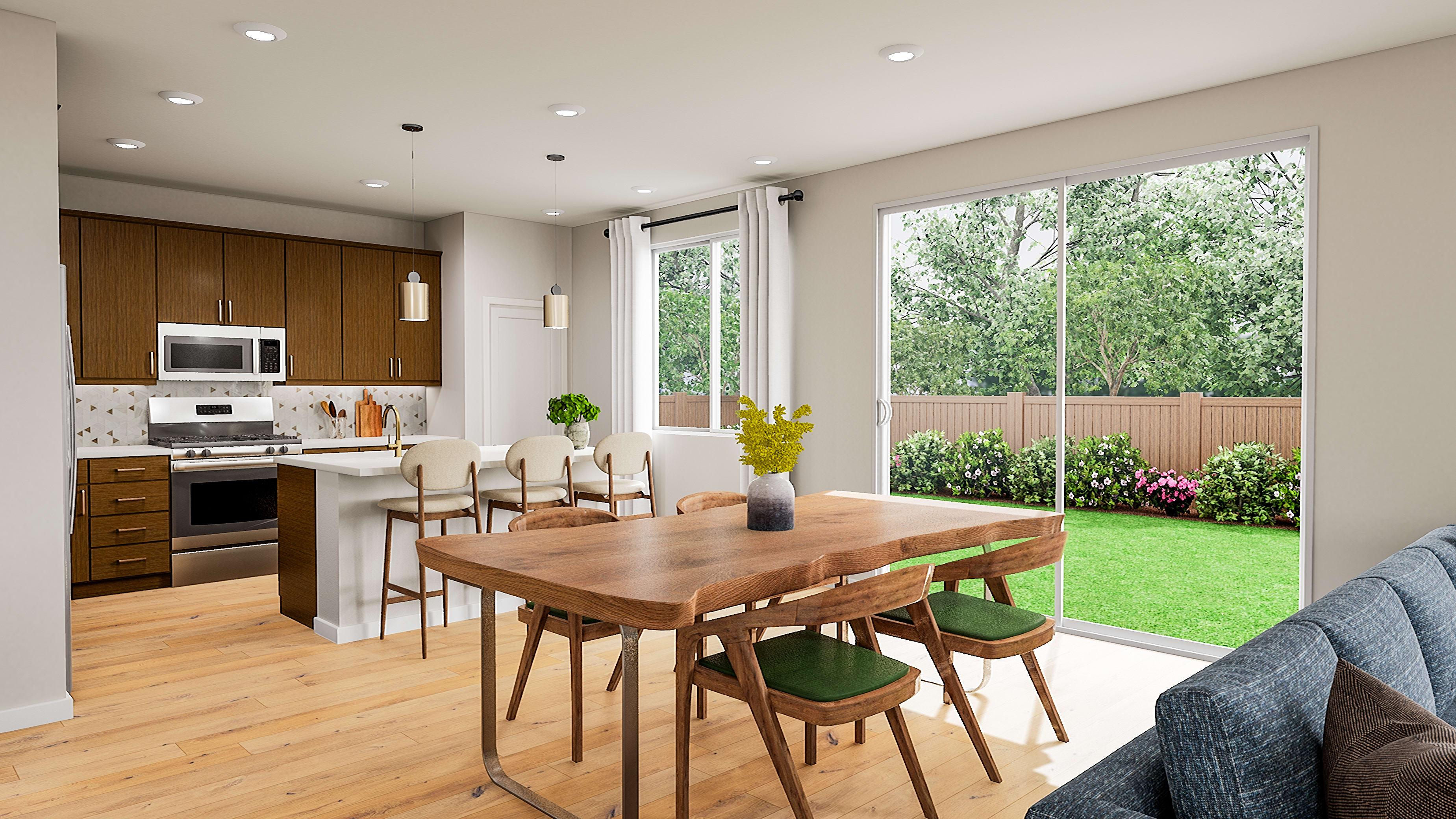 A modern kitchen and dining area with a lush green backyard visible through large sliding glass doors.
