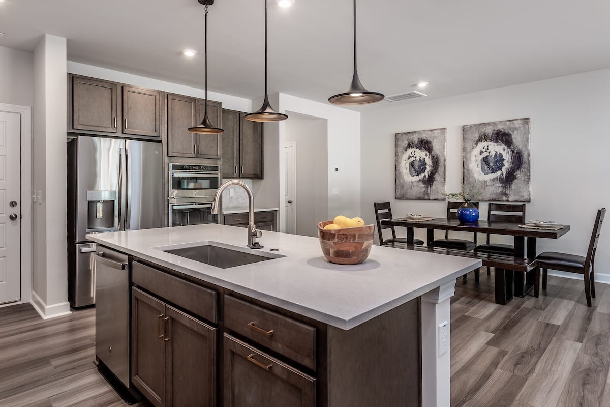 A modern and well-designed kitchen with a large island, stainless steel appliances, and artwork on the walls, creating a warm and inviting atmosphere.