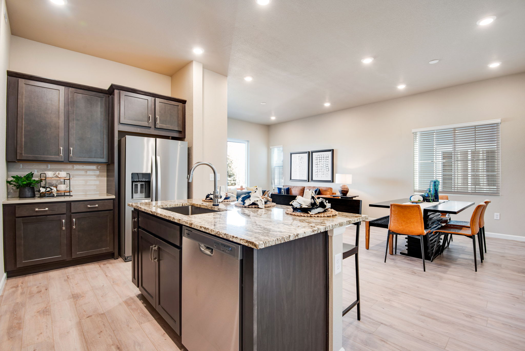 A modern and spacious kitchen with dark wood cabinets, granite countertops, and stainless steel appliances, leading into a dining area with a table and chairs.