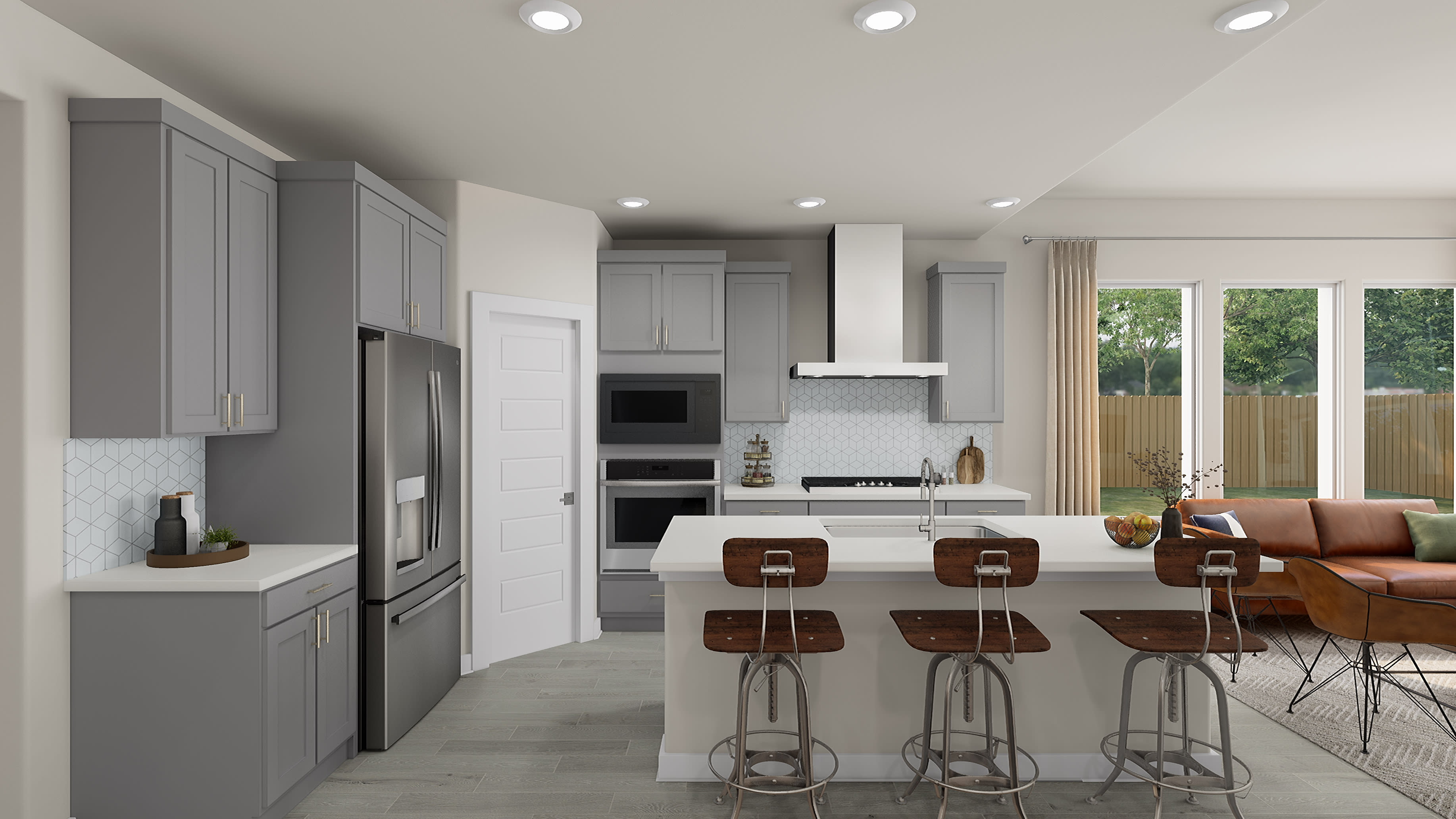 A modern, open-concept kitchen with gray cabinets, stainless steel appliances, and a cozy seating area with a leather sofa in the background.