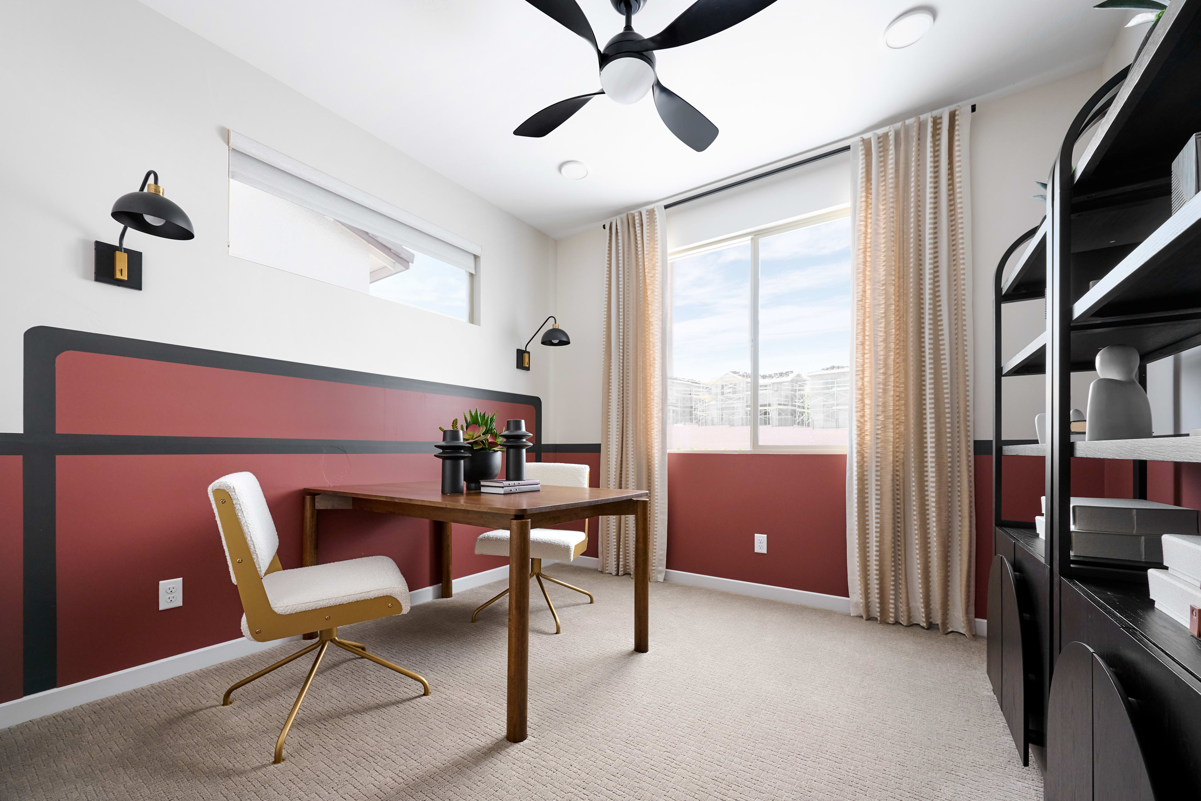 A modern home office with a wooden desk and chairs in the foreground is set against a backdrop of large windows revealing a suburban landscape.