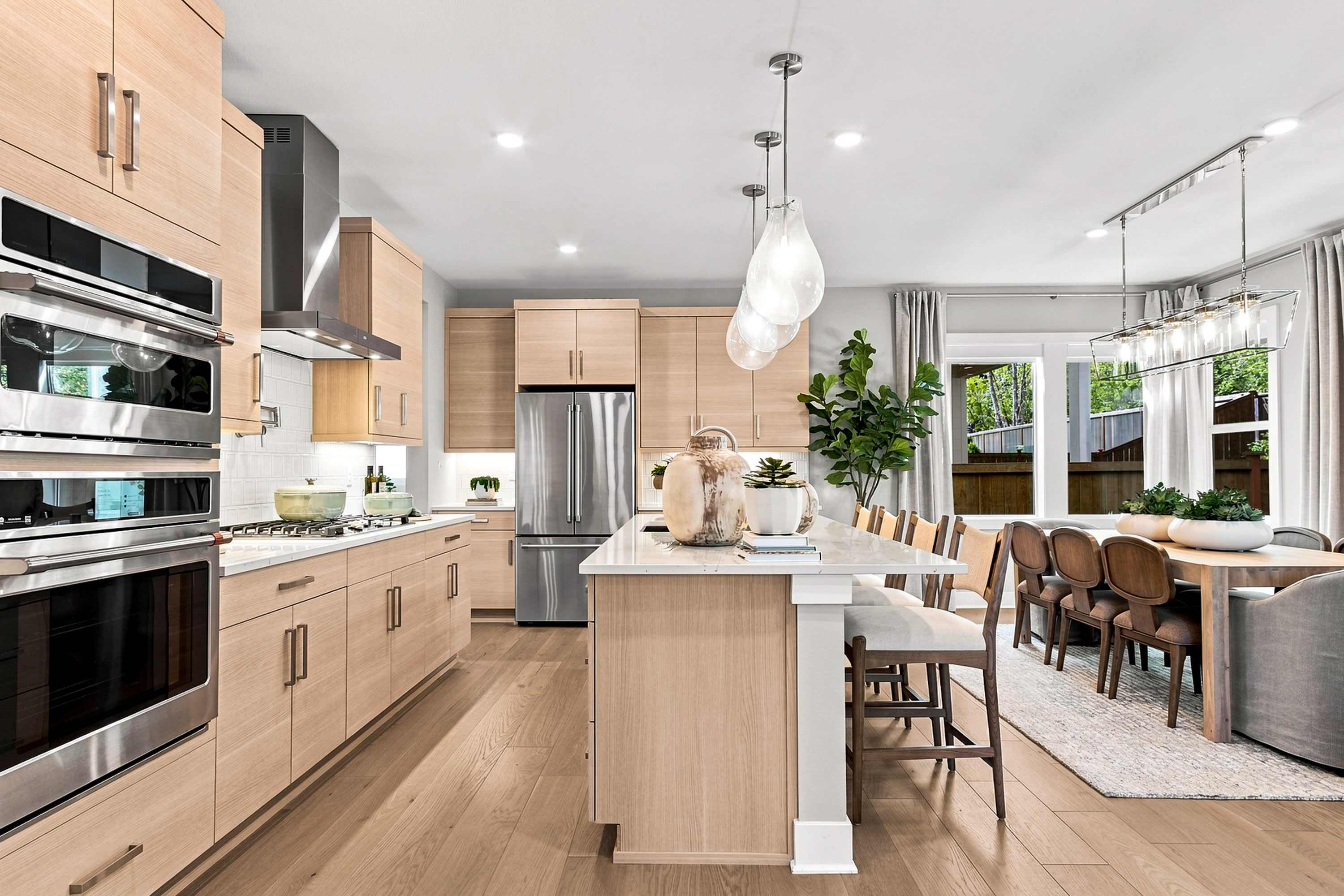 A modern kitchen with a large island in the foreground and a dining area with a table and chairs in the background.