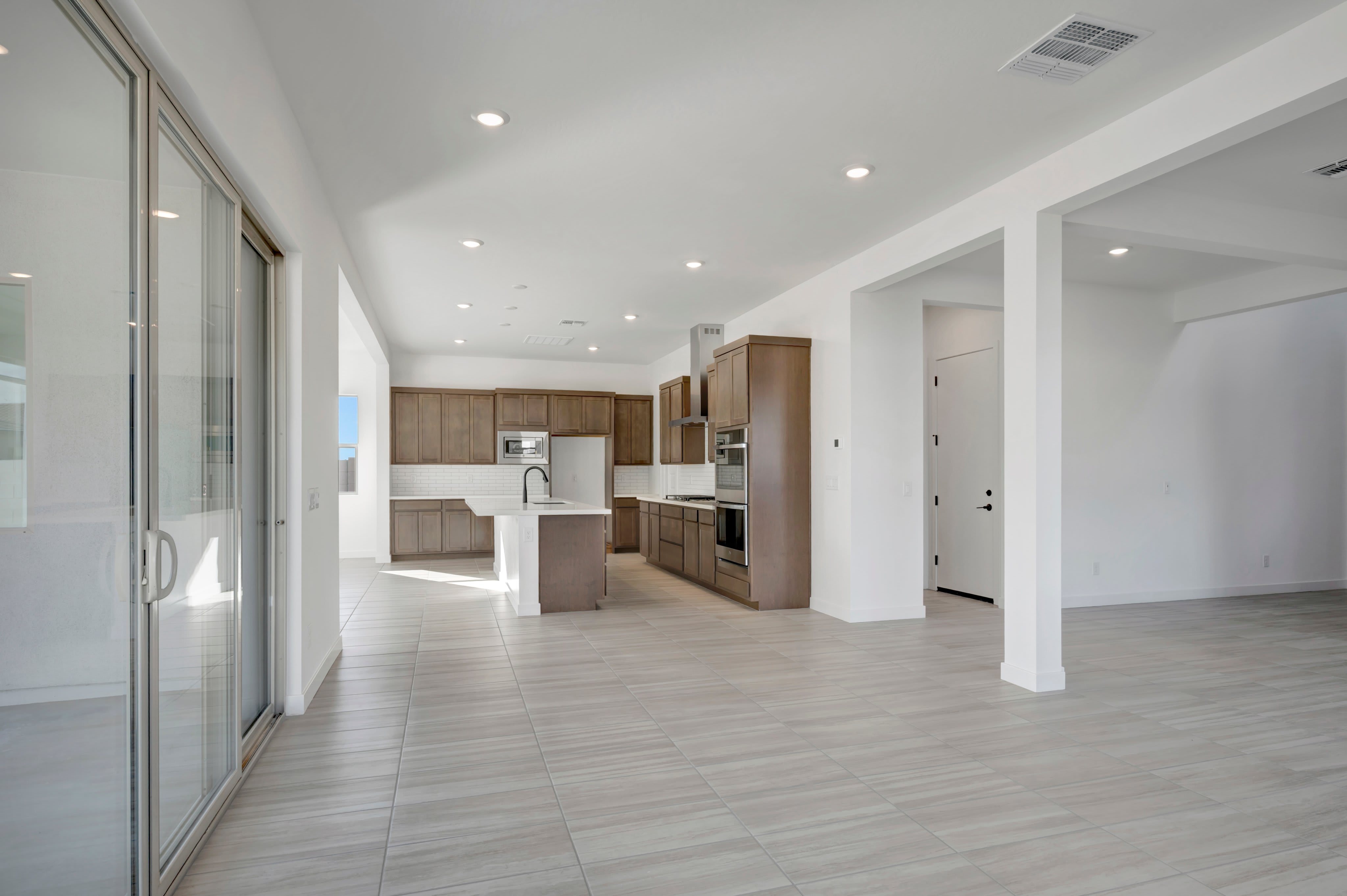 A modern, open-concept living space with a sleek kitchen in the background and large glass doors in the foreground.