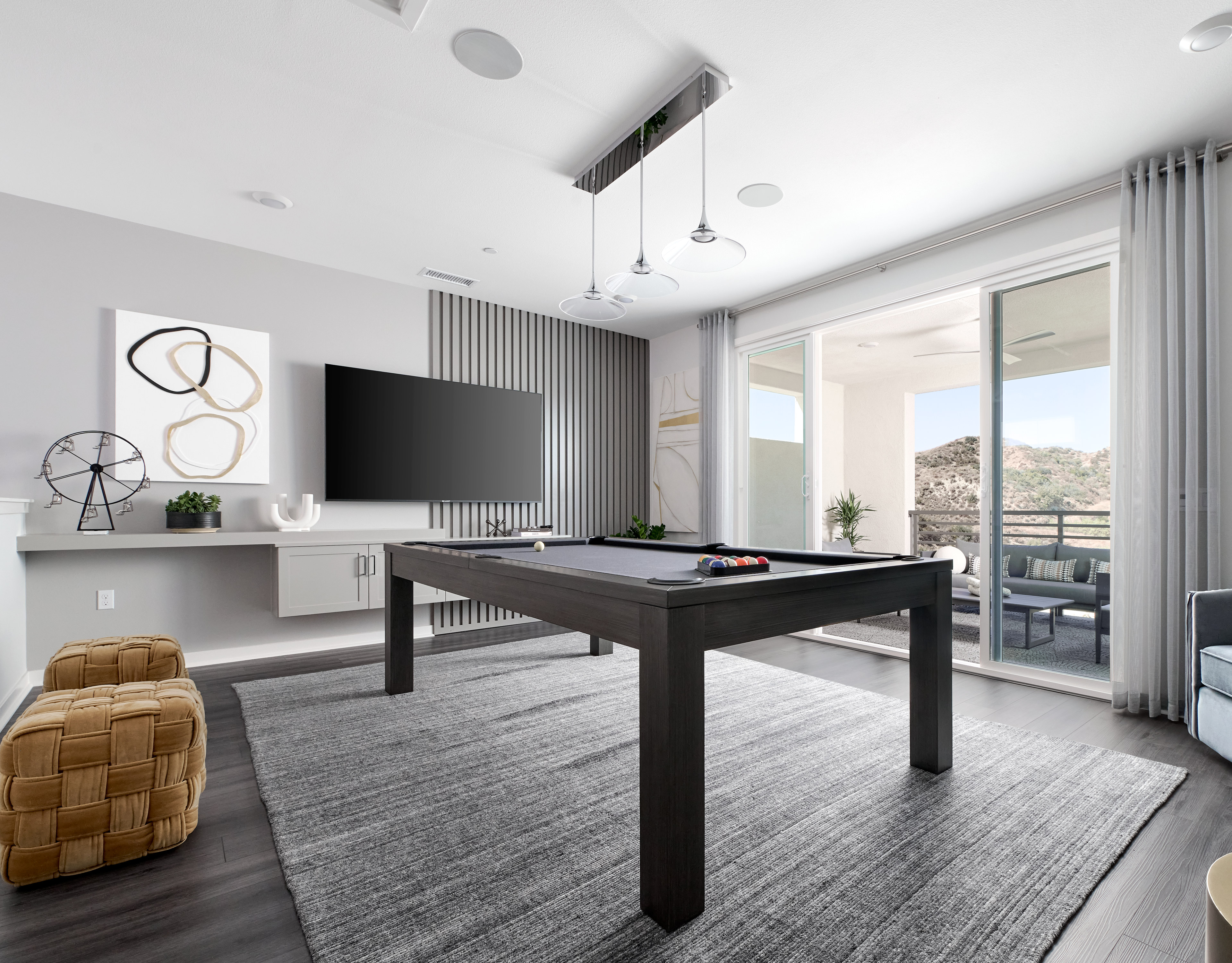 A modern and stylish living room with a pool table, large windows, and various decorative elements.