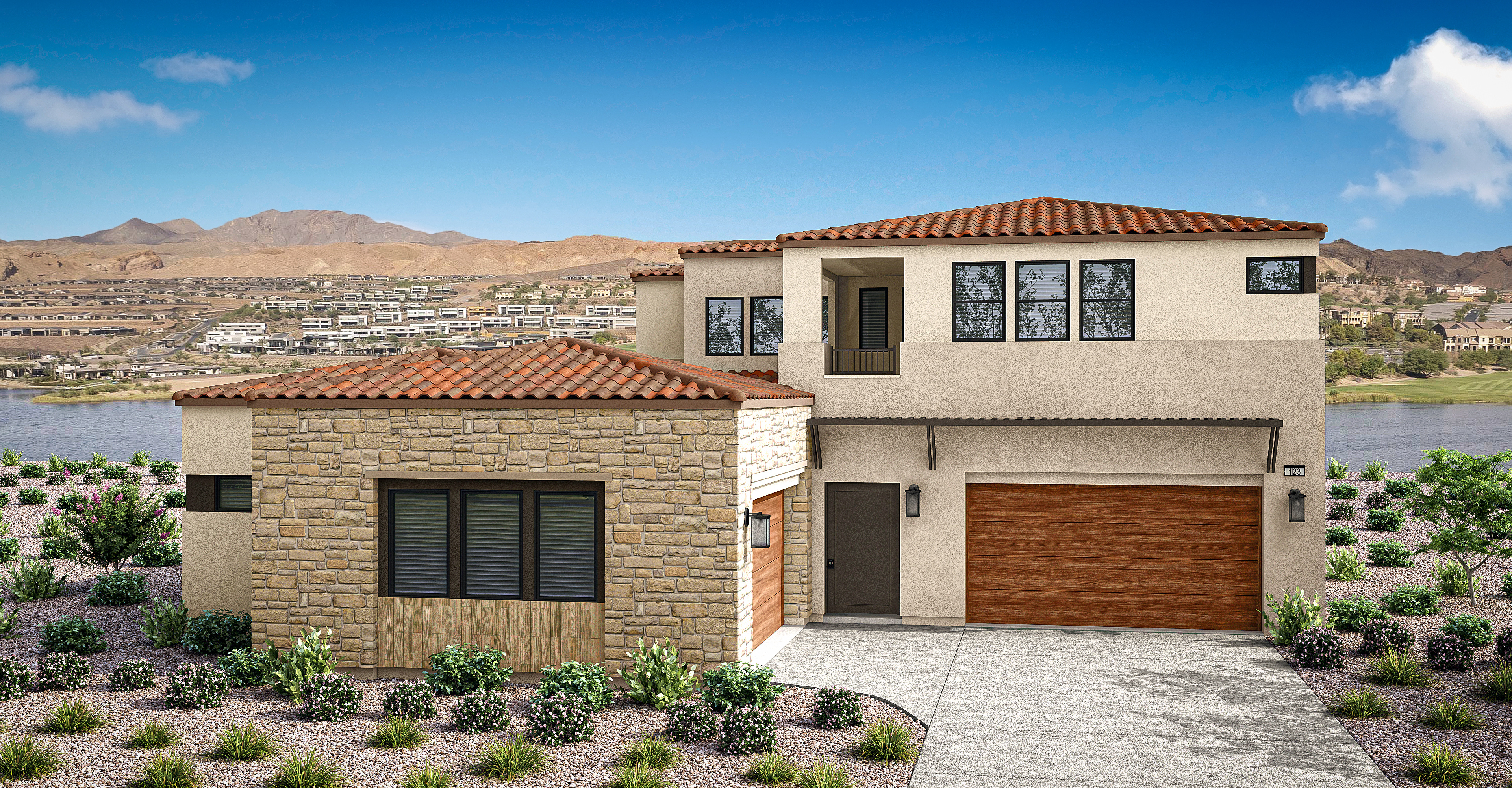 A two-story Mediterranean-style house with a tiled roof, stone exterior, and a wooden garage door sits in the foreground, surrounded by lush landscaping, with a mountainous desert landscape visible in the background under a bright blue sky.