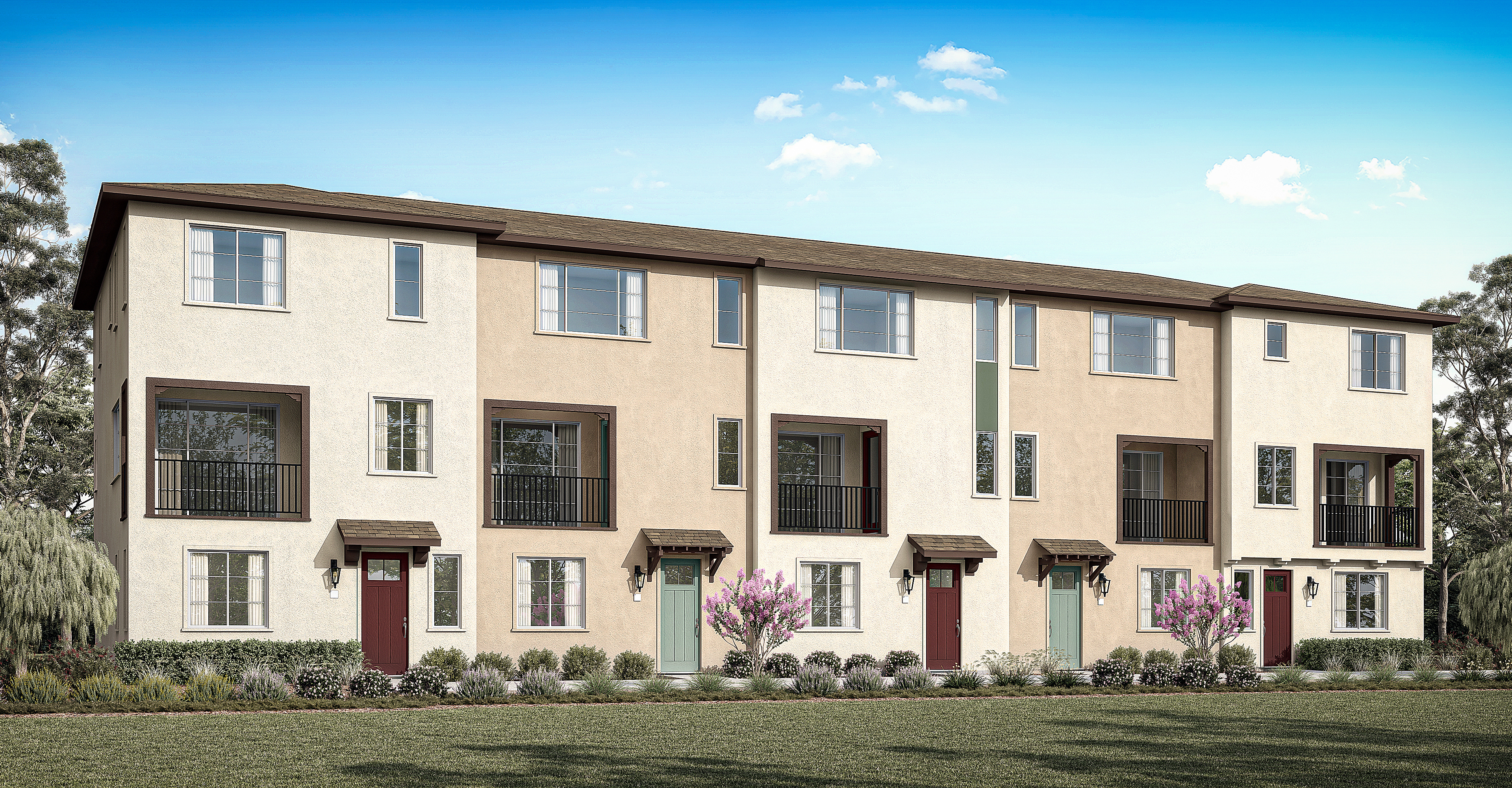 A row of modern, two-story townhouses with beige exteriors and red doors, surrounded by lush greenery and a clear blue sky.