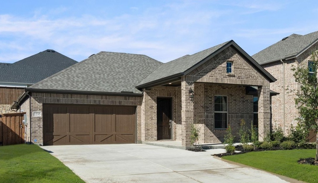 A two-story brick house with a garage, surrounded by a well-manicured lawn and set against a backdrop of clear blue skies.