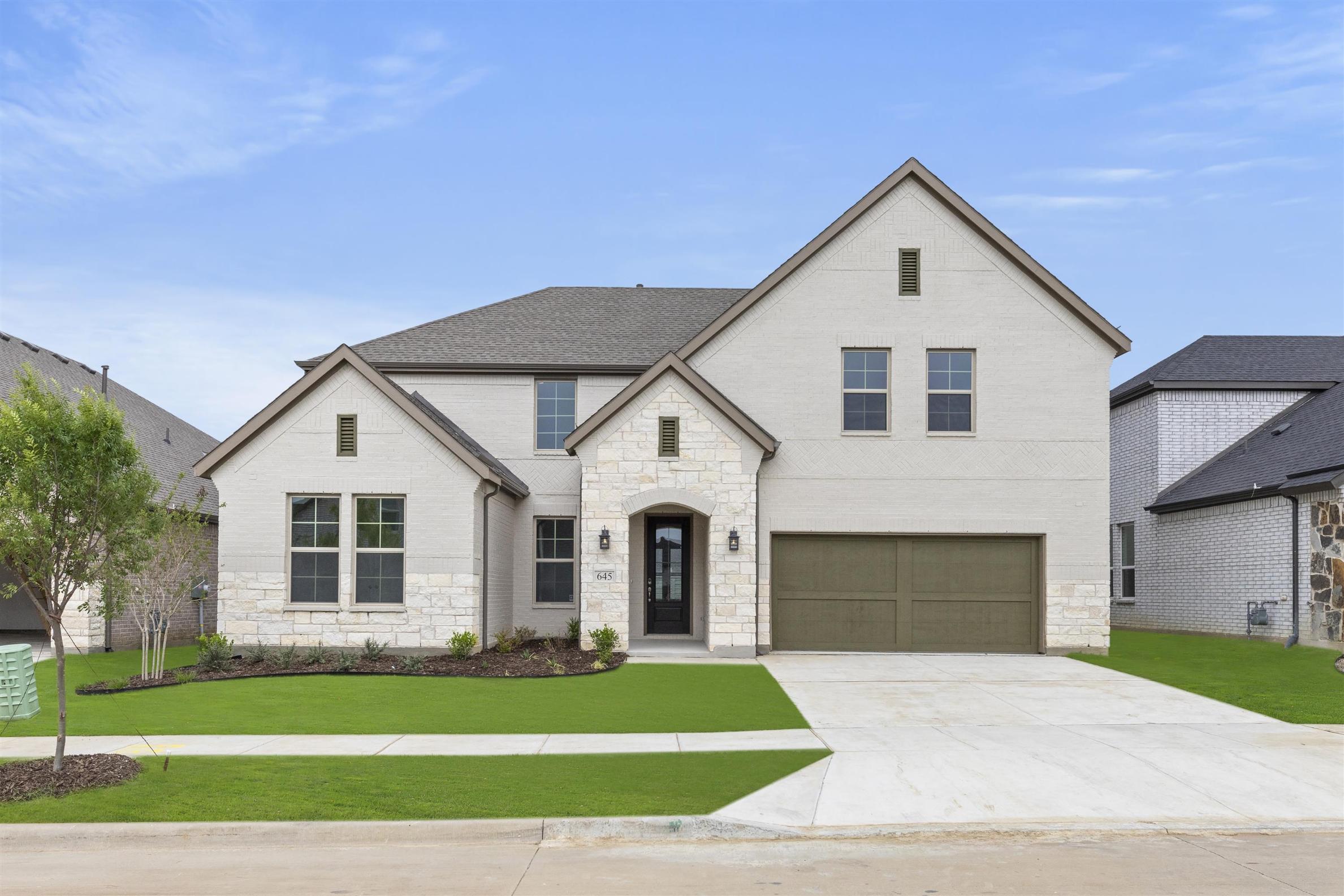 A two-story white house with a gabled roof, a front porch, and a well-manicured lawn in the foreground, set against a clear blue sky in the background.