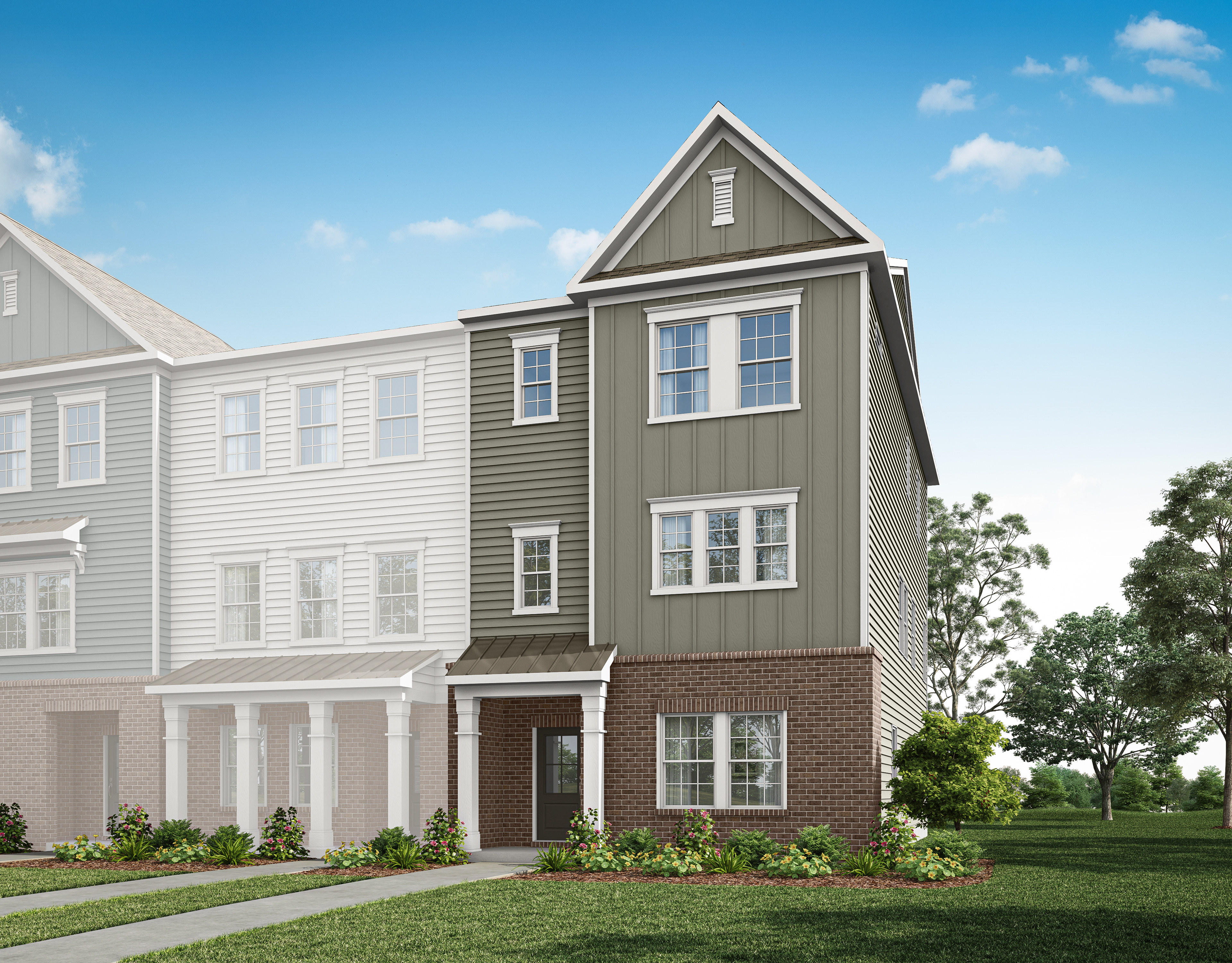 A multi-story townhouse with a gray exterior, white trim, and a brick foundation sits in a grassy area with trees in the background.