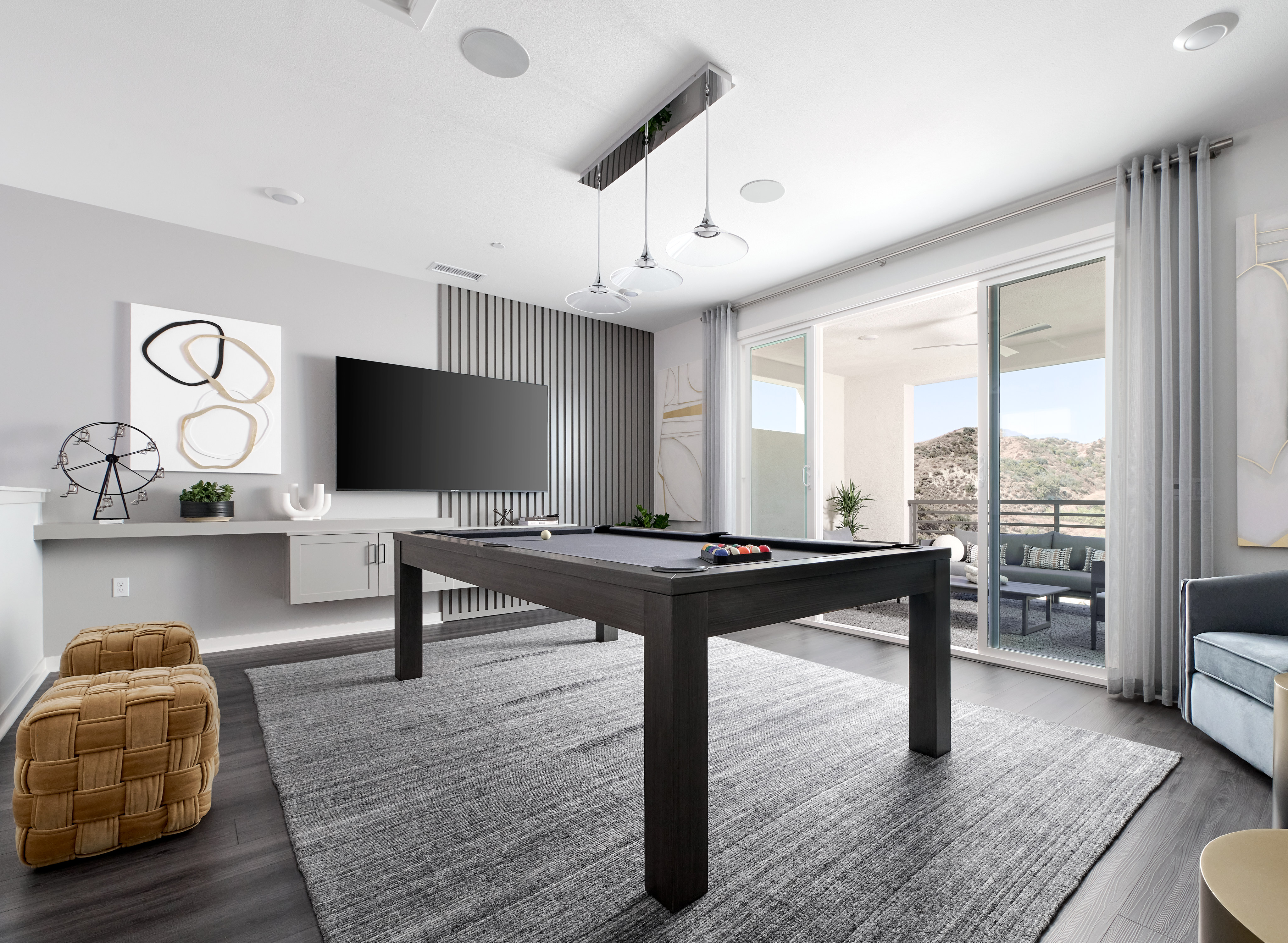 A modern and stylish living room with a pool table, large windows, and various decorative elements.