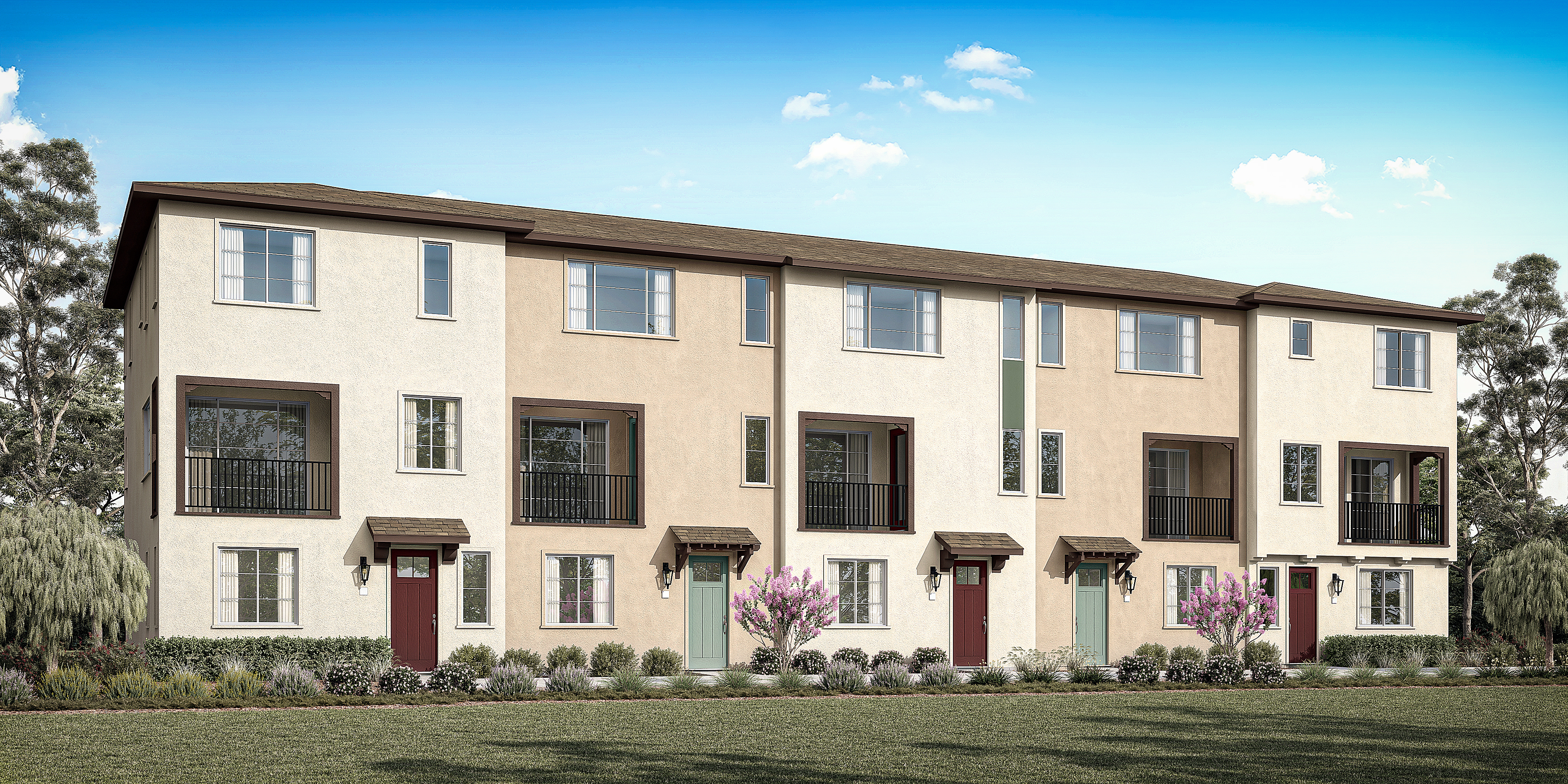 A row of modern, two-story townhouses with beige exteriors and red doors, surrounded by lush greenery and a clear blue sky.