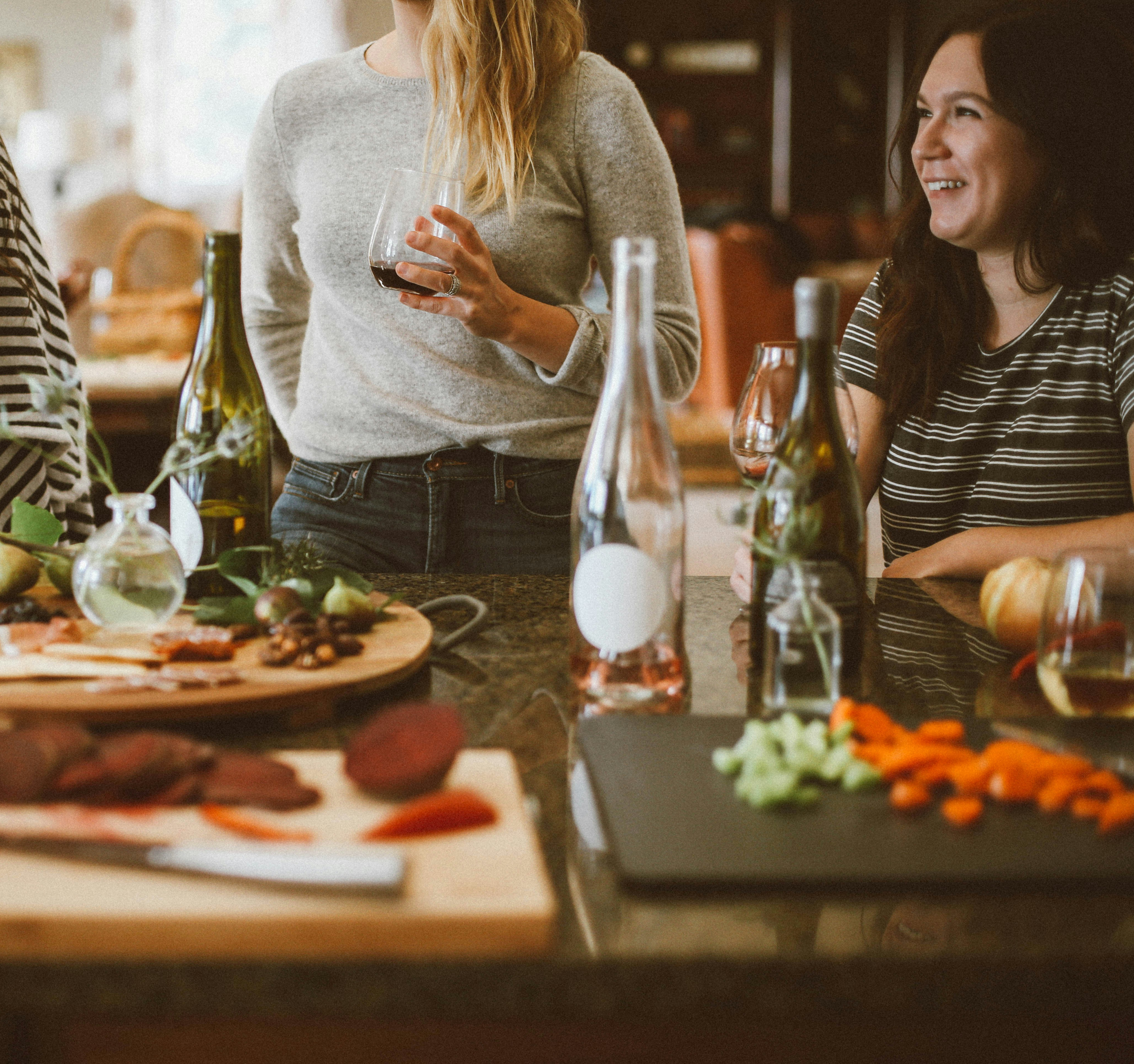 A cozy gathering of friends enjoying a meal together, with a table full of delectable dishes and drinks in a warm, inviting setting.