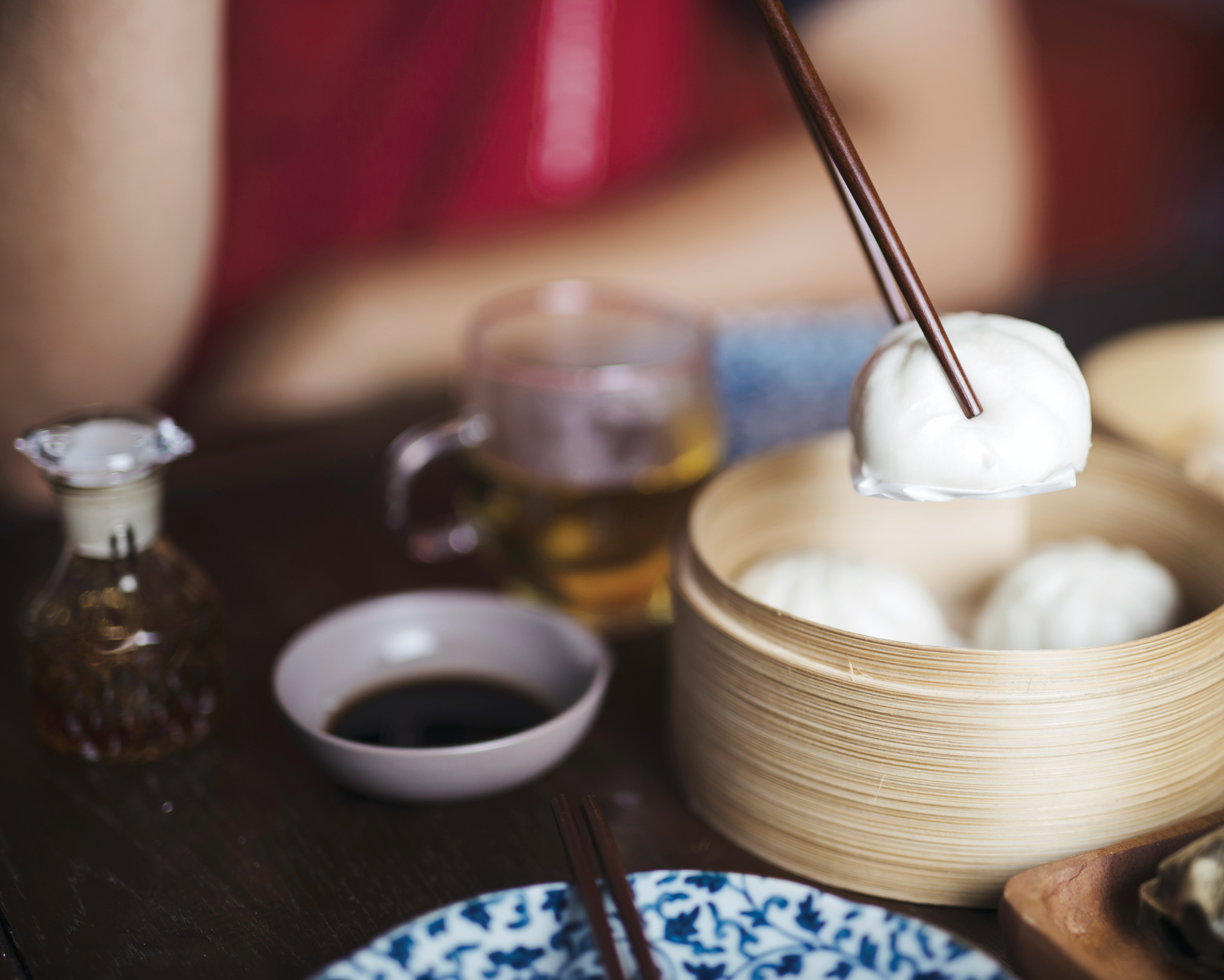 A wooden container filled with white marshmallows, accompanied by various condiments and utensils, set against a dark background.
