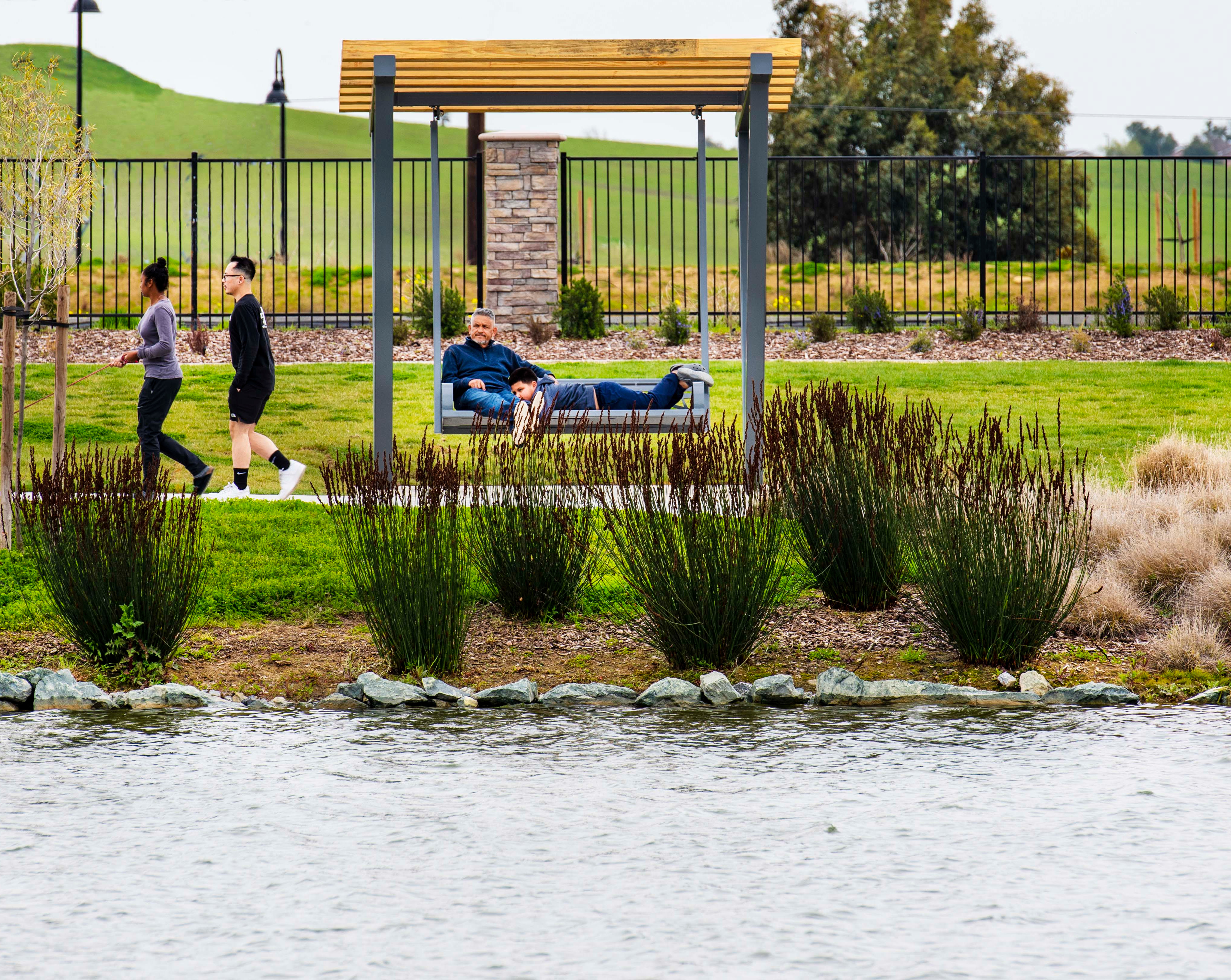 A well-designed outdoor public space with a grassy area, a bench, and people enjoying the surroundings.
