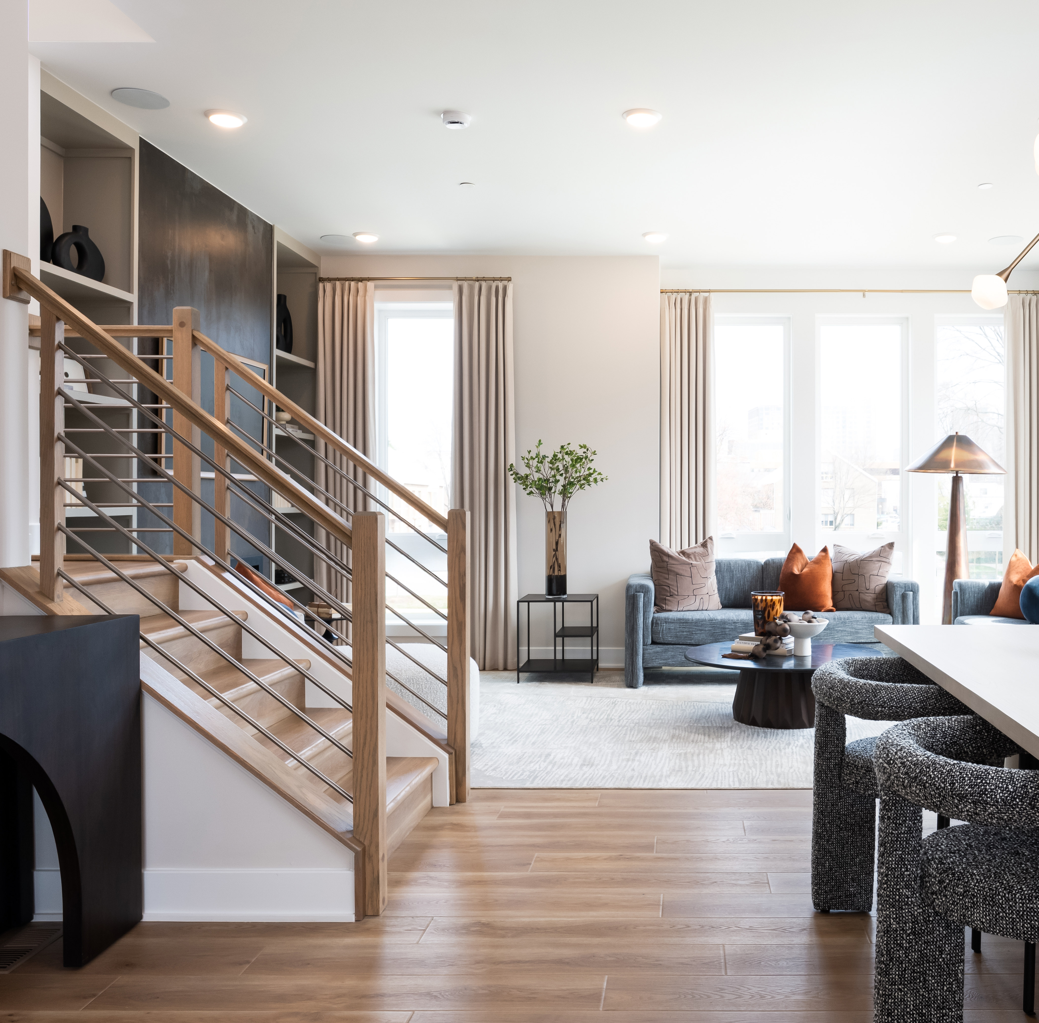 A modern and stylish living room with a wooden staircase, plush seating, and decorative accents, creating a warm and inviting atmosphere.