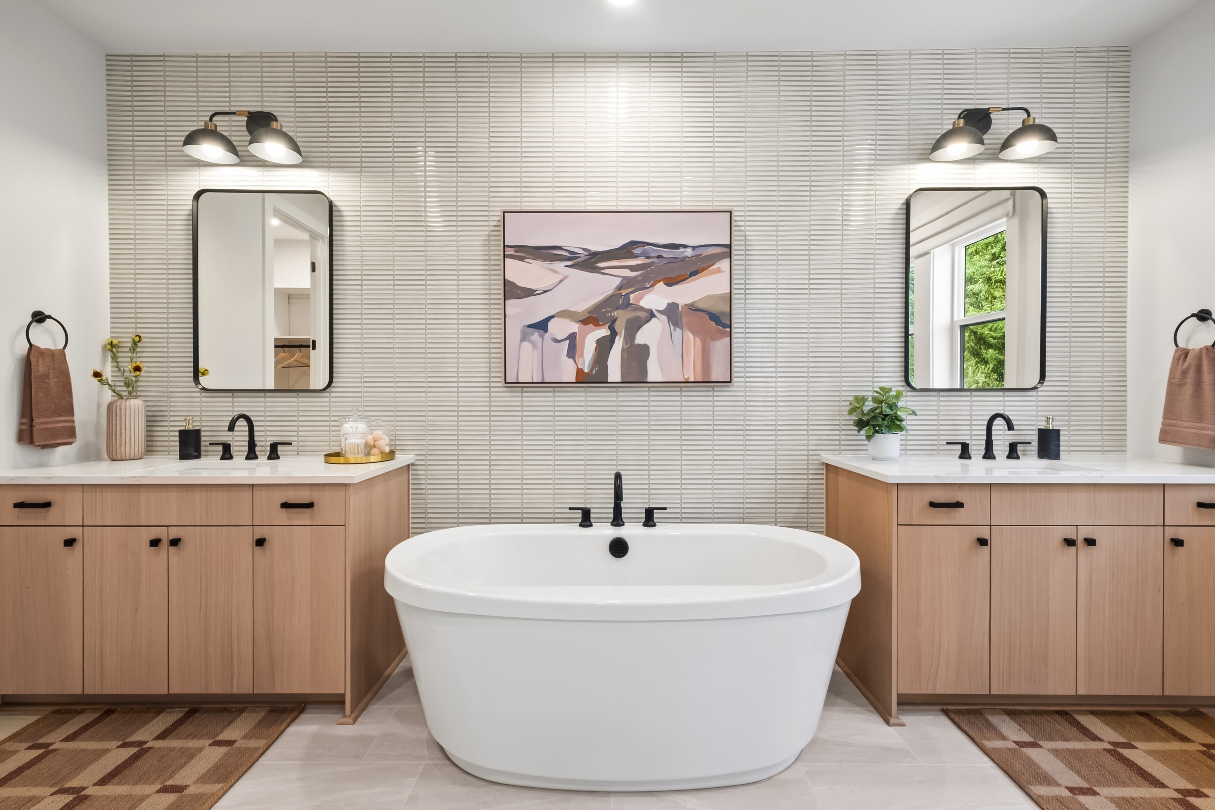 A modern and minimalist bathroom with a freestanding bathtub, double vanity, and abstract artwork on the wall.