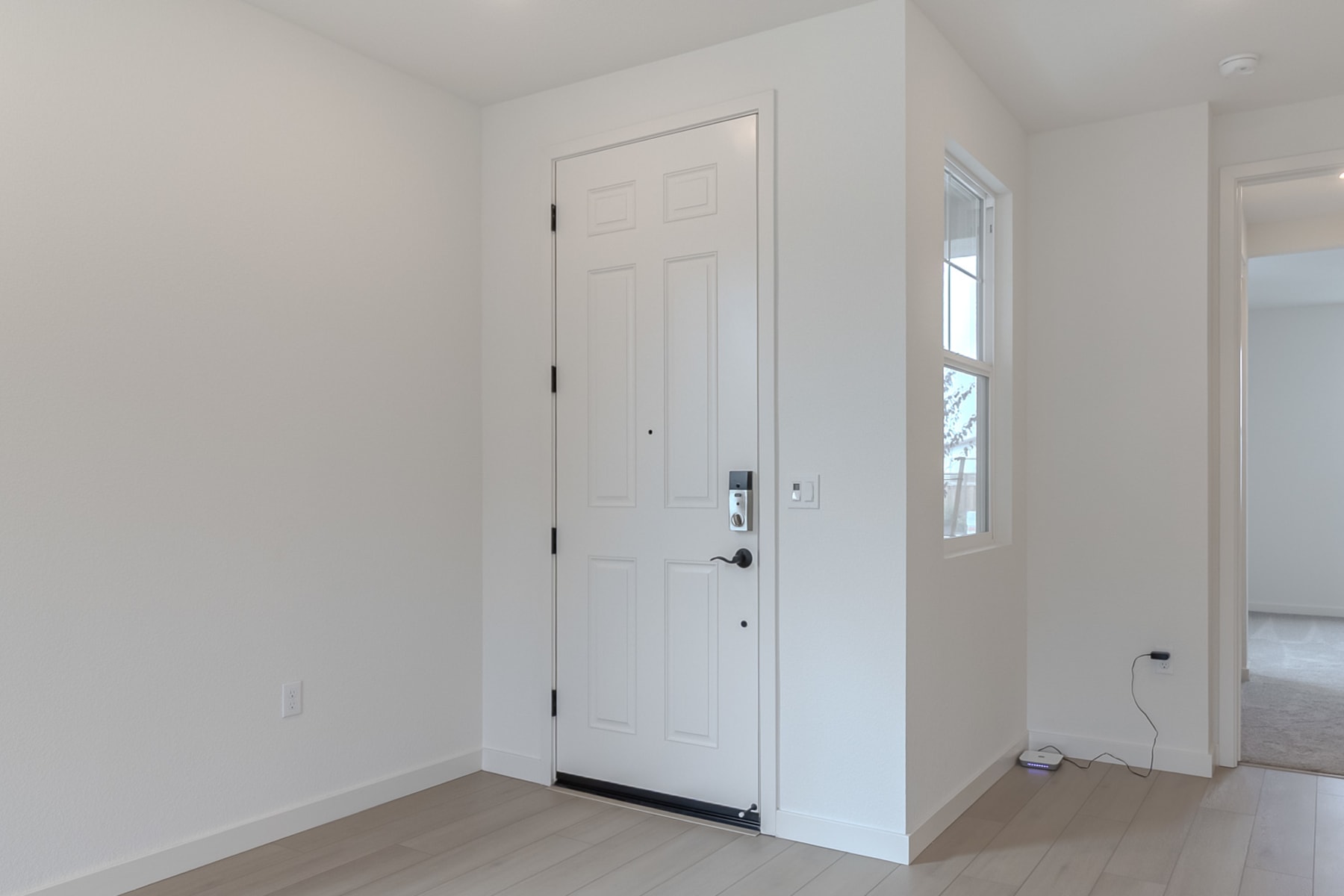 A white door stands in the center of a bright, minimalist room with light-colored walls and floors.