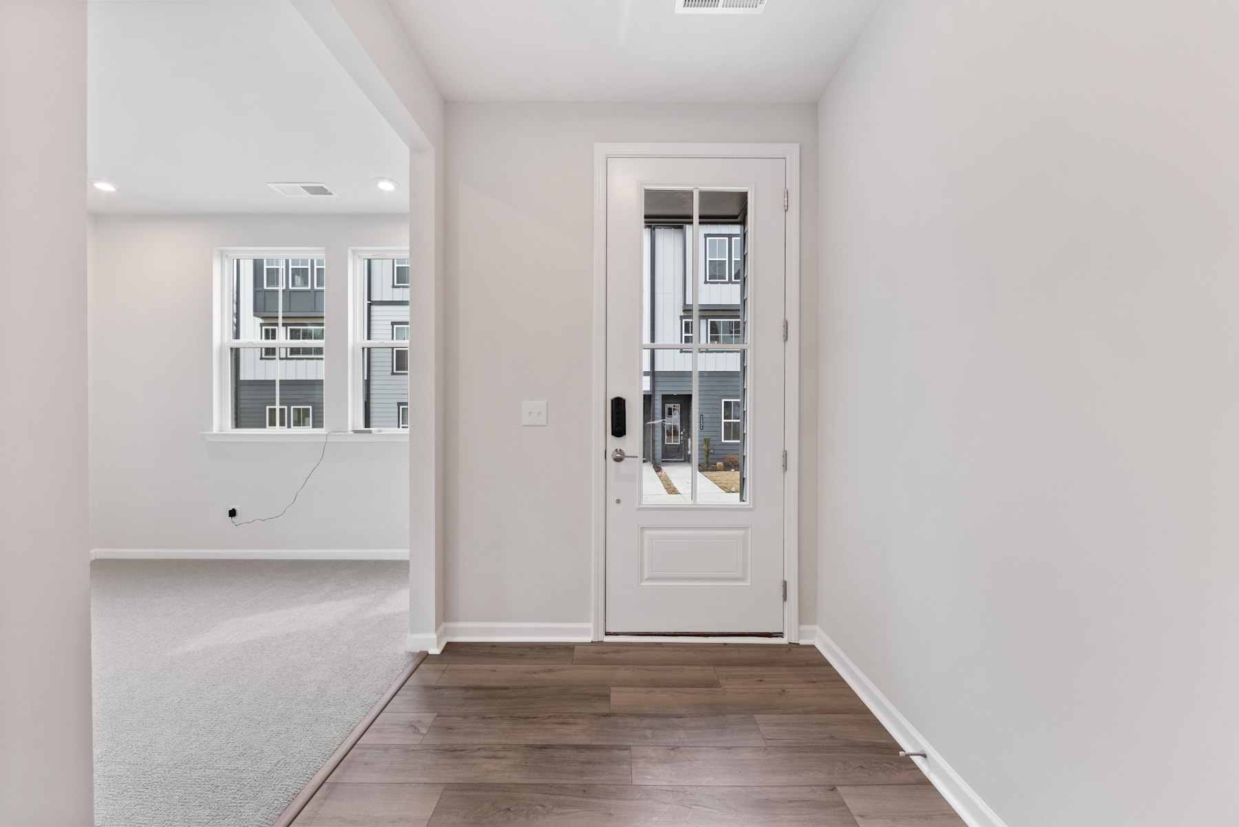 A bright and spacious entryway with a white door, hardwood floors, and a minimalist design.