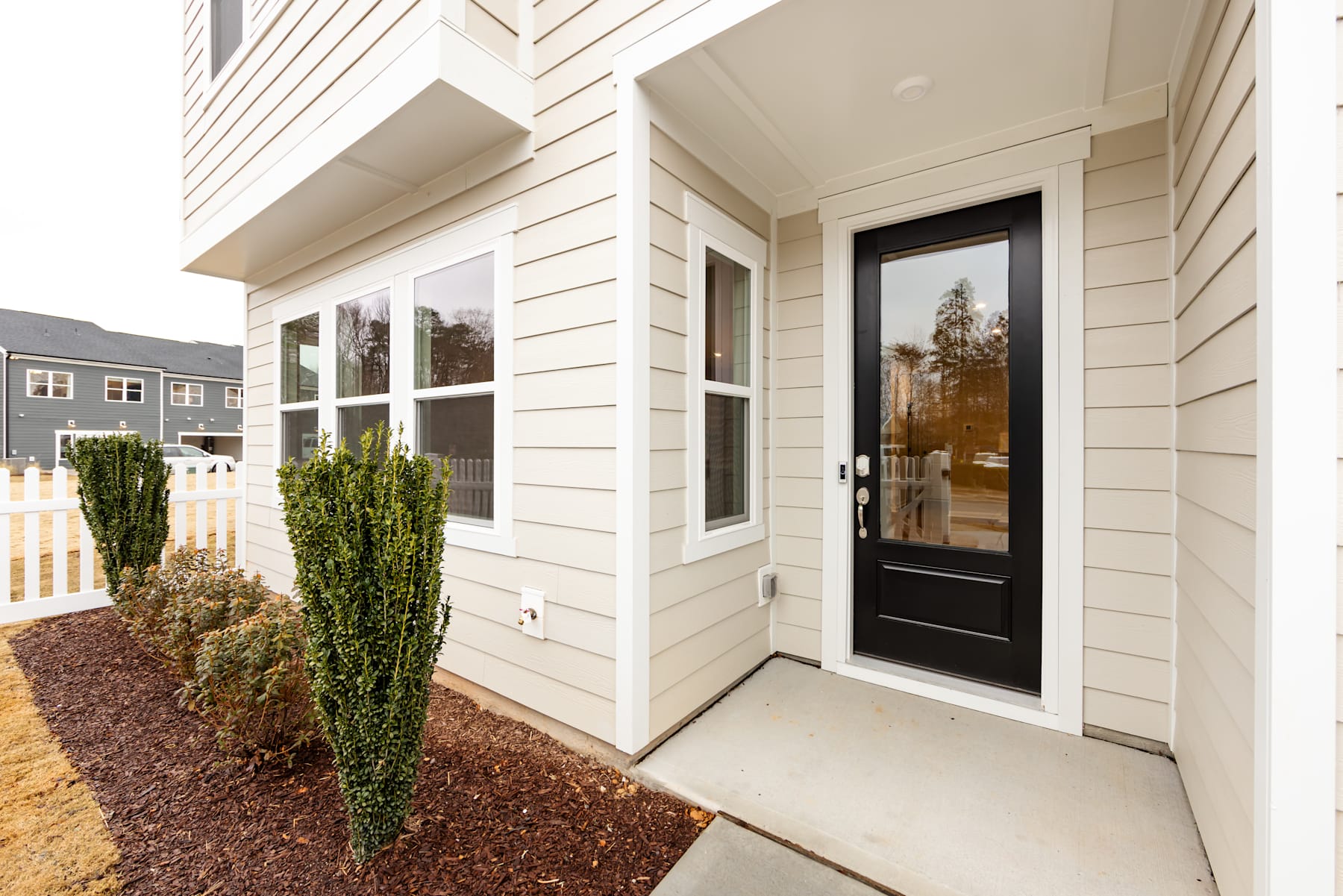 A well-maintained residential home with a porch, surrounded by landscaped greenery and a paved walkway leading to the front door.