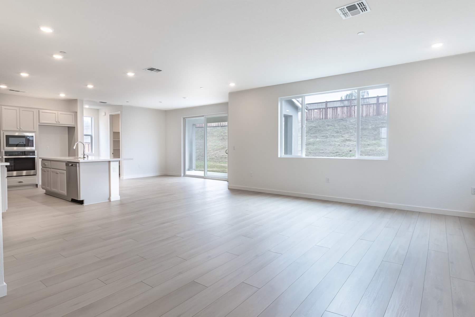 A spacious, open-concept living area with a modern kitchen, hardwood floors, and large windows providing ample natural light.