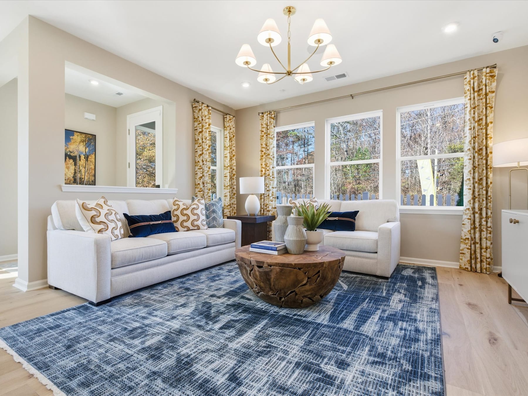 A cozy and well-decorated living room with plush sofas, a patterned rug, and a large window overlooking a scenic outdoor view.