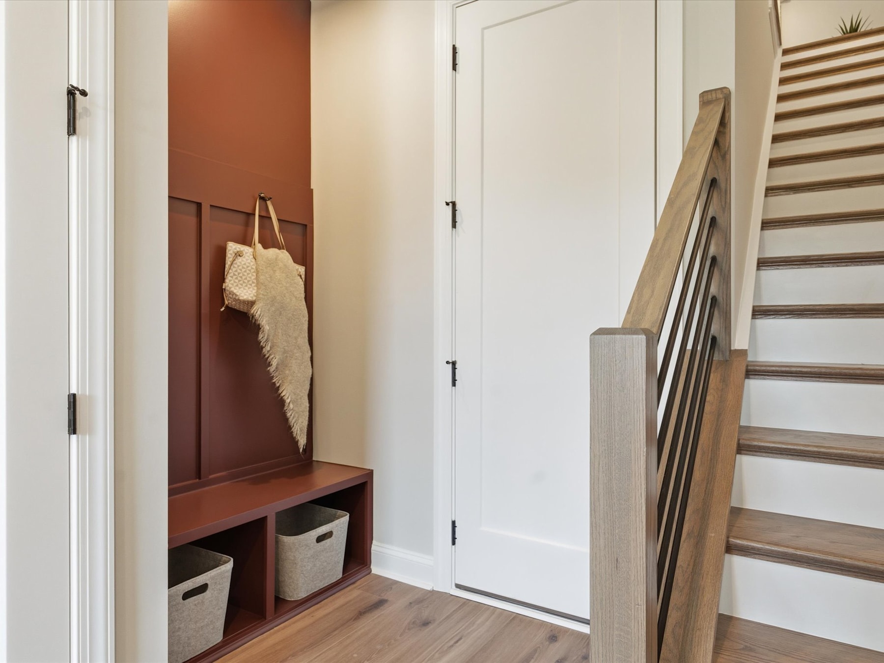 A cozy entryway with a wooden bench, storage cubbies, and a white door leading to another room.
