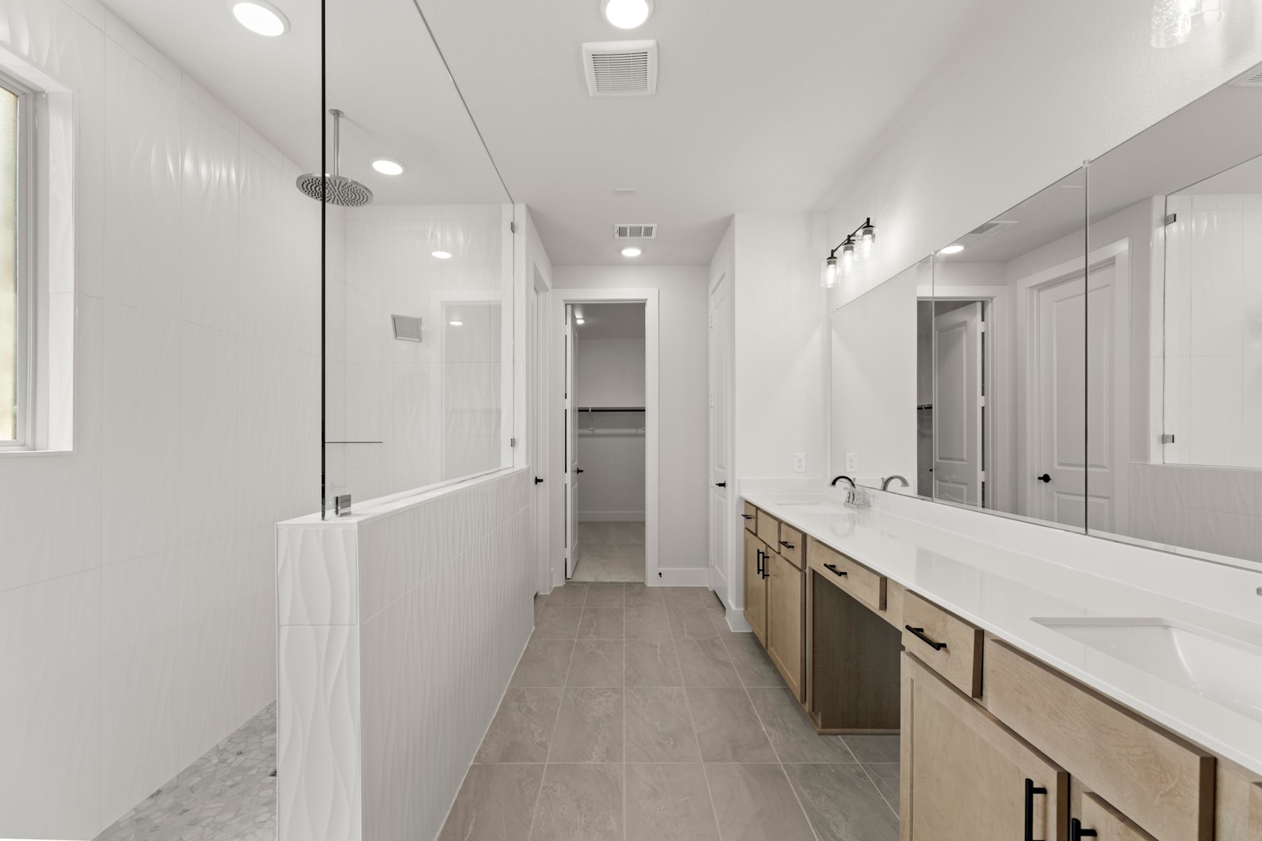 A long, narrow hallway with white walls, a tiled floor, and a vanity with drawers and cabinets along one side.