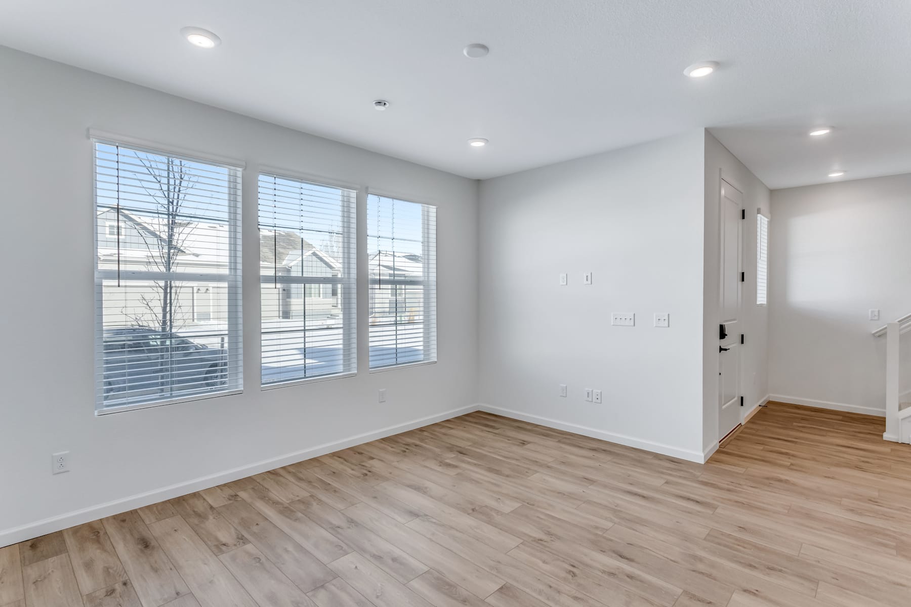 A spacious, well-lit room with large windows, hardwood floors, and a neutral color scheme, creating a clean and modern atmosphere.