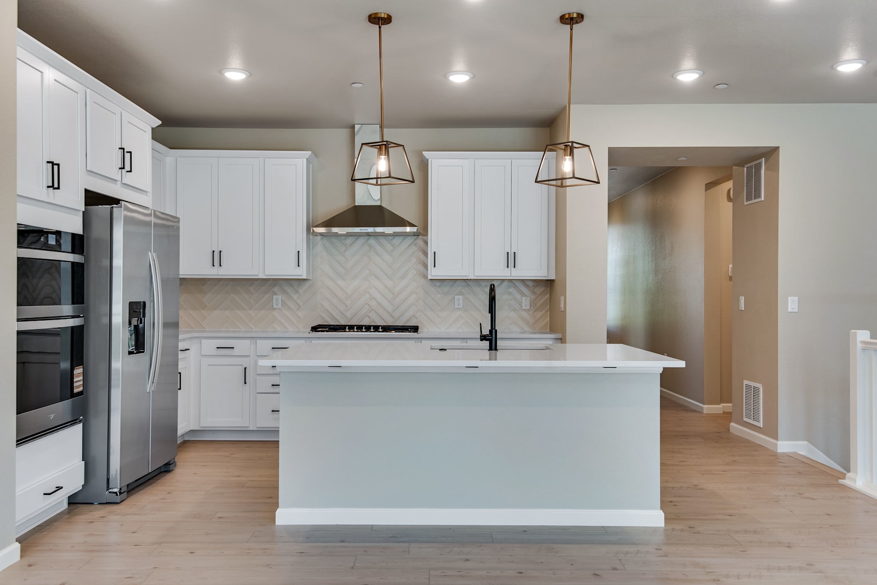 A modern, well-lit kitchen with white cabinets, a central island, and pendant lighting fixtures.