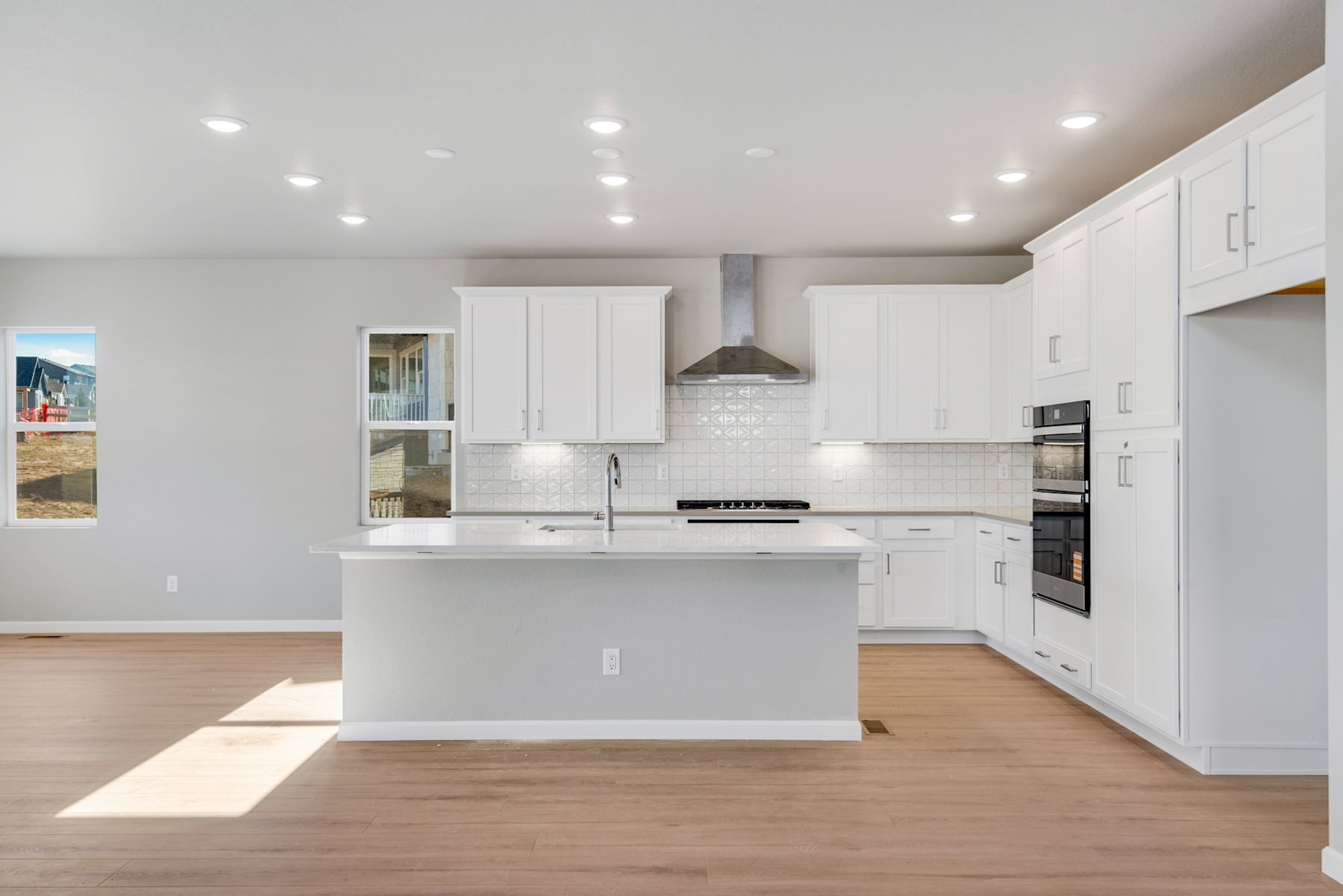 A modern, bright, and spacious kitchen with white cabinets, a central island, and hardwood floors.