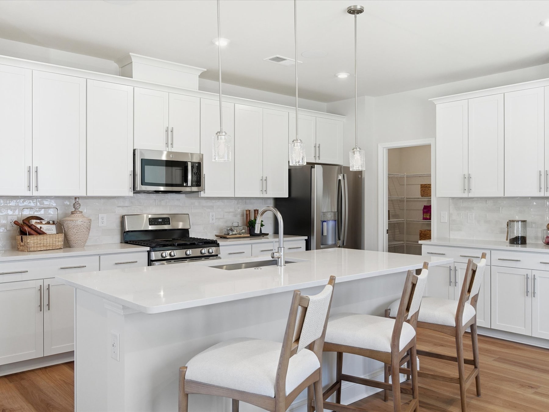 A modern, bright, and spacious kitchen with white cabinets, a large island, and stainless steel appliances.