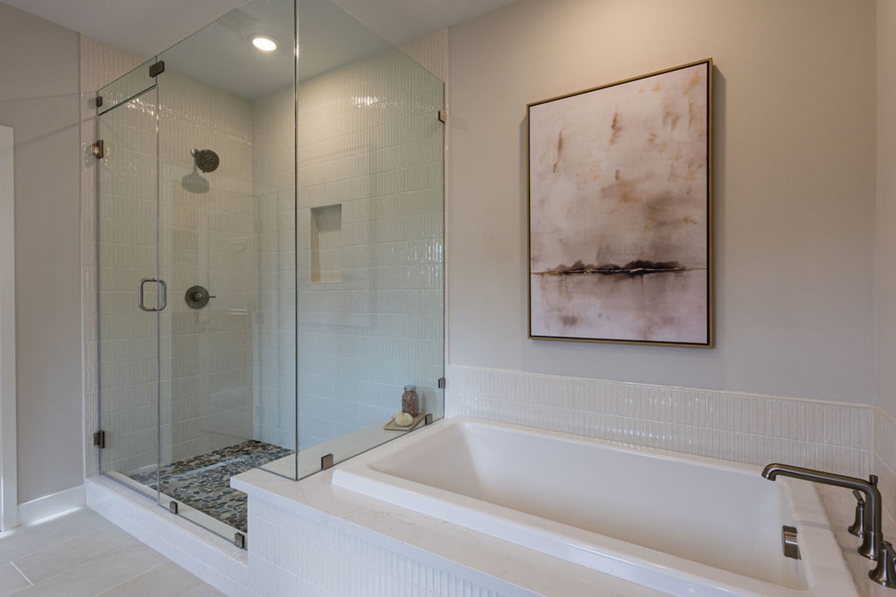 A modern bathroom with a large glass-enclosed shower, a freestanding bathtub, and a framed abstract artwork on the wall.