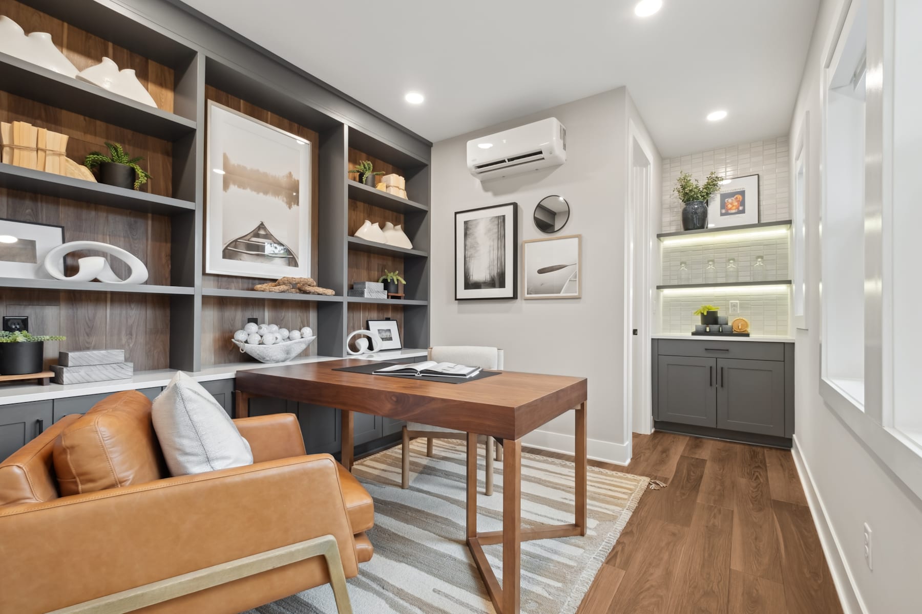 A cozy and well-designed home office space with wooden shelves, a desk, and a comfortable leather chair, set against a neutral color palette and accented with decorative elements.