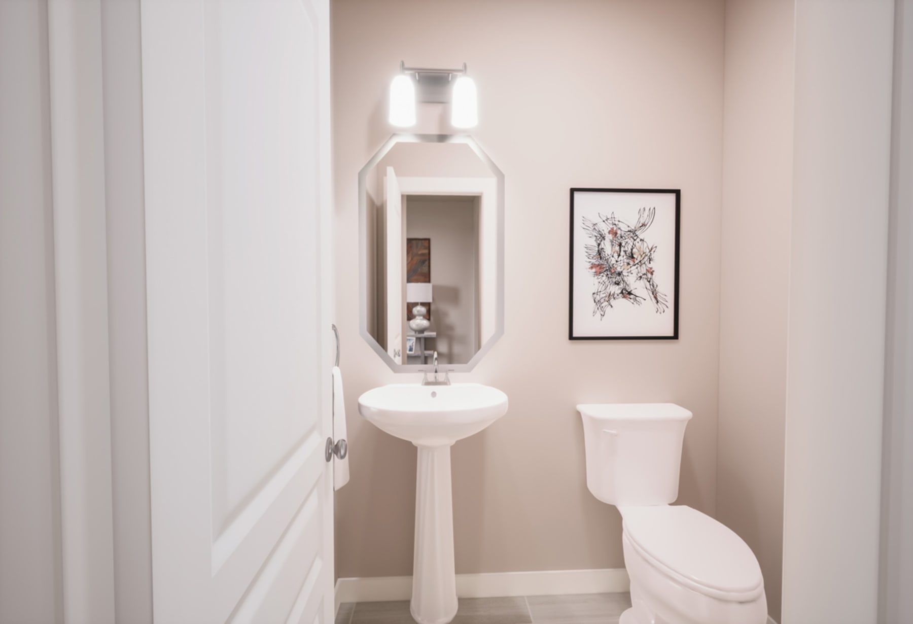 A minimalist bathroom with a white pedestal sink, a toilet, and a framed artwork on the wall.