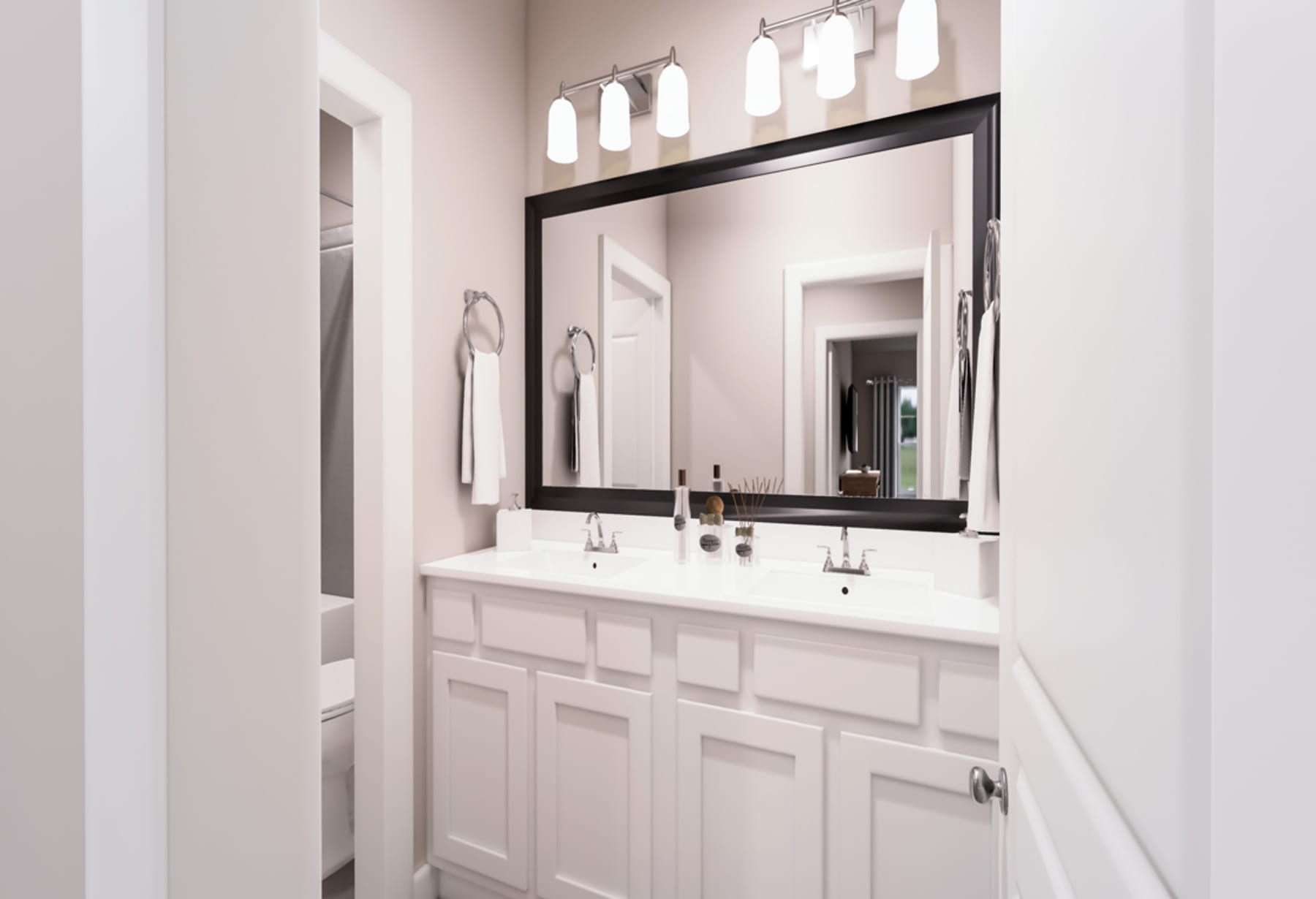 A well-lit bathroom with a large mirror, white cabinets, and a double vanity sink.
