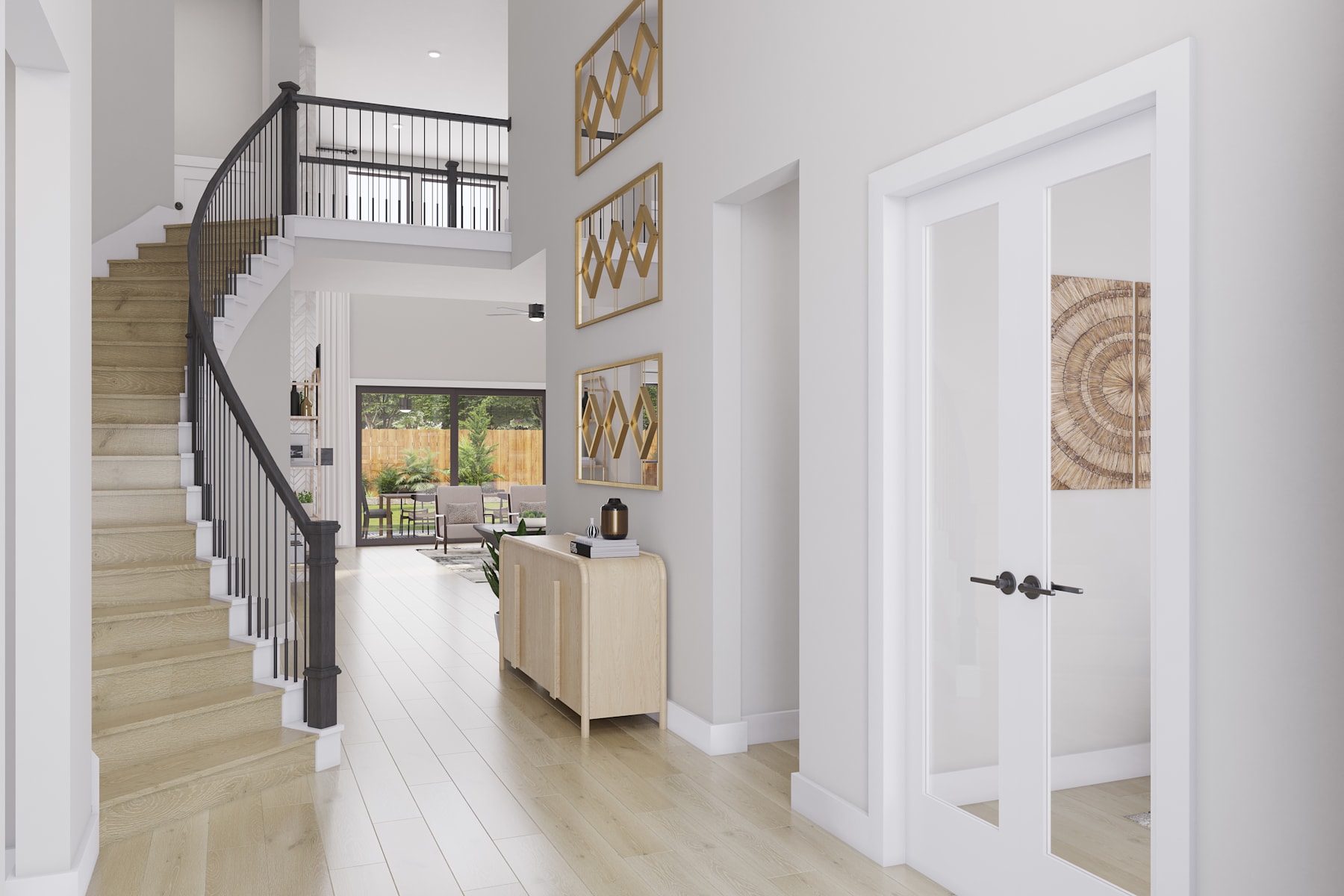 A bright and airy entryway with a wooden staircase, white walls, and decorative artwork on the walls, leading to a view of the outdoors through a glass door.