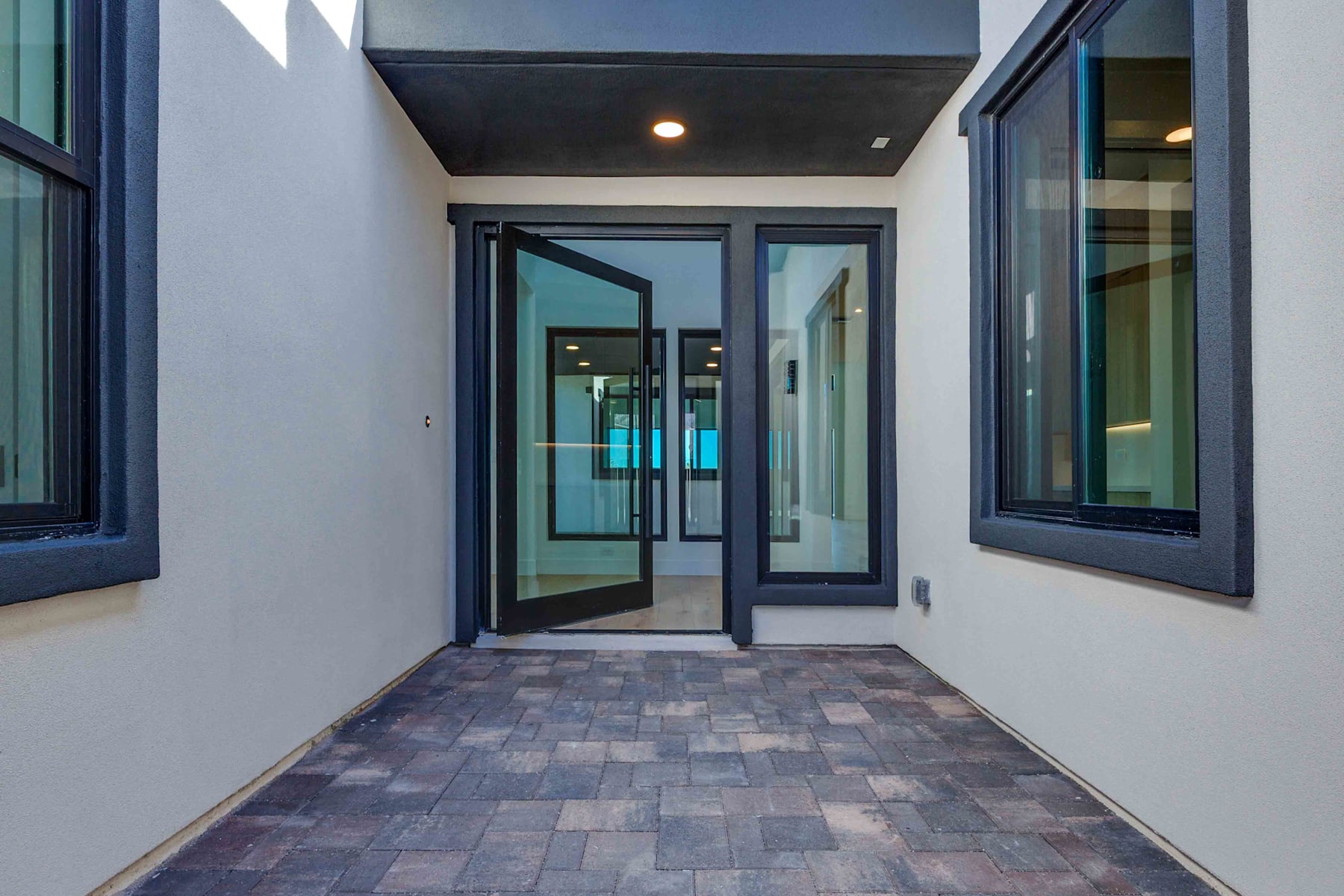 A modern, glass-enclosed entryway with a tiled floor leads into a brightly lit interior space.