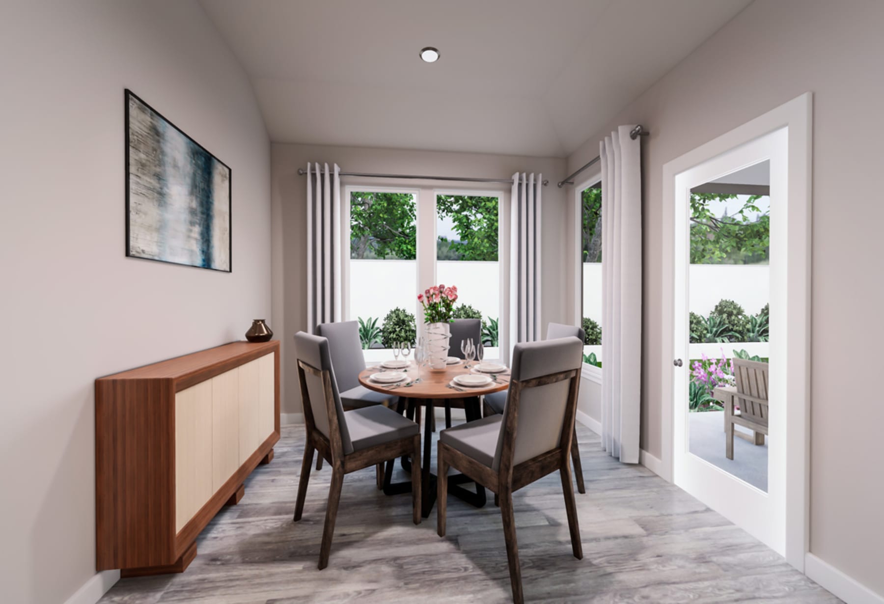A cozy dining area with a wooden table and chairs, surrounded by large windows that provide a view of the lush greenery outside.