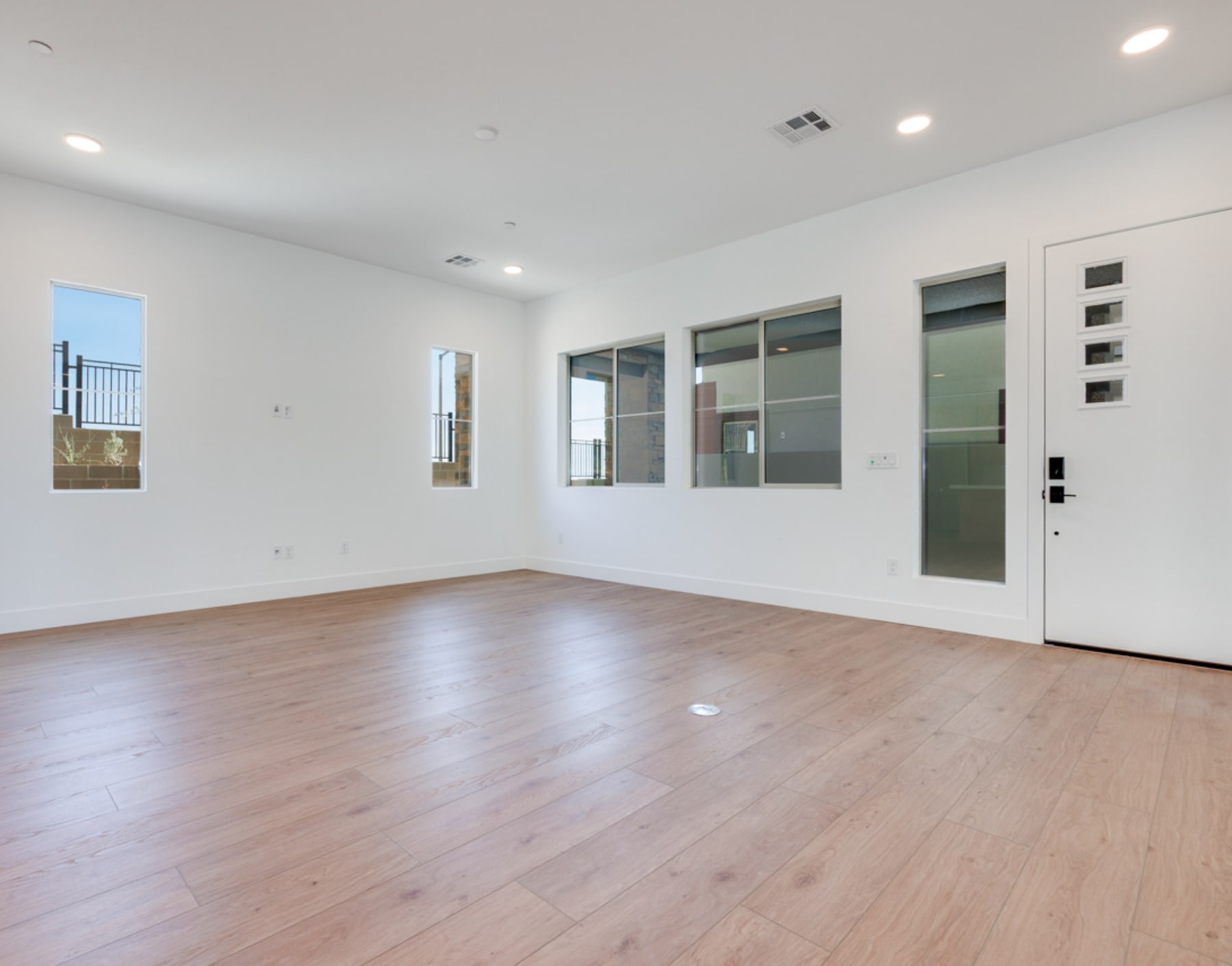 A spacious, well-lit room with a wooden floor, white walls, and large windows providing natural light. The room appears to be an empty living space or office, ready for furnishing and personalization.