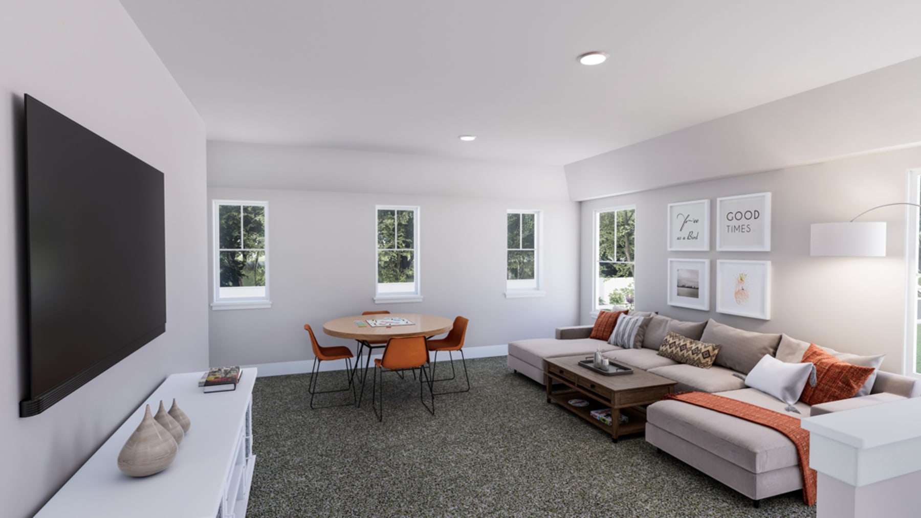 A modern and minimalist living room with a gray sofa, wooden dining table, and framed artwork on the walls, surrounded by large windows overlooking the outdoors.