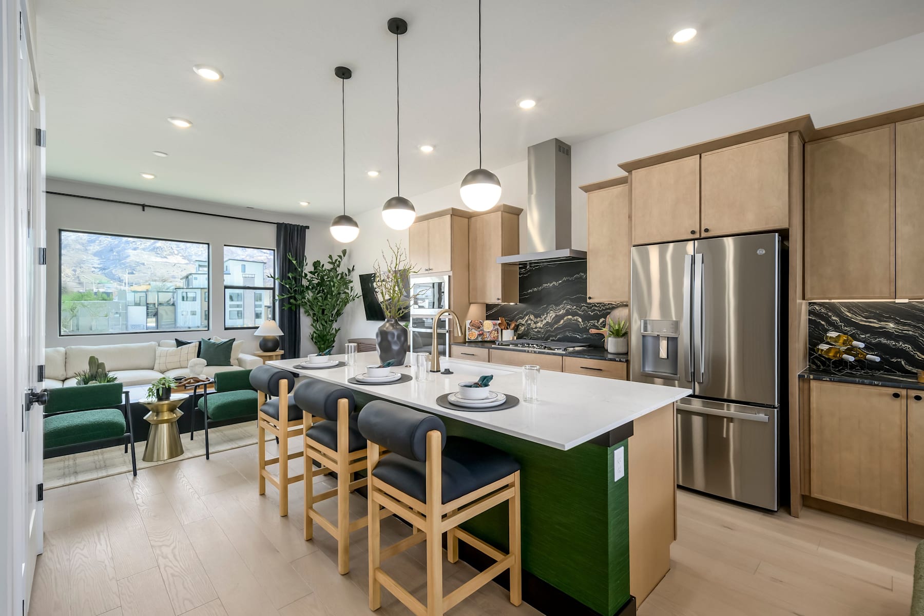 A modern and stylish kitchen with a large island, pendant lights, and a cozy seating area in the background.