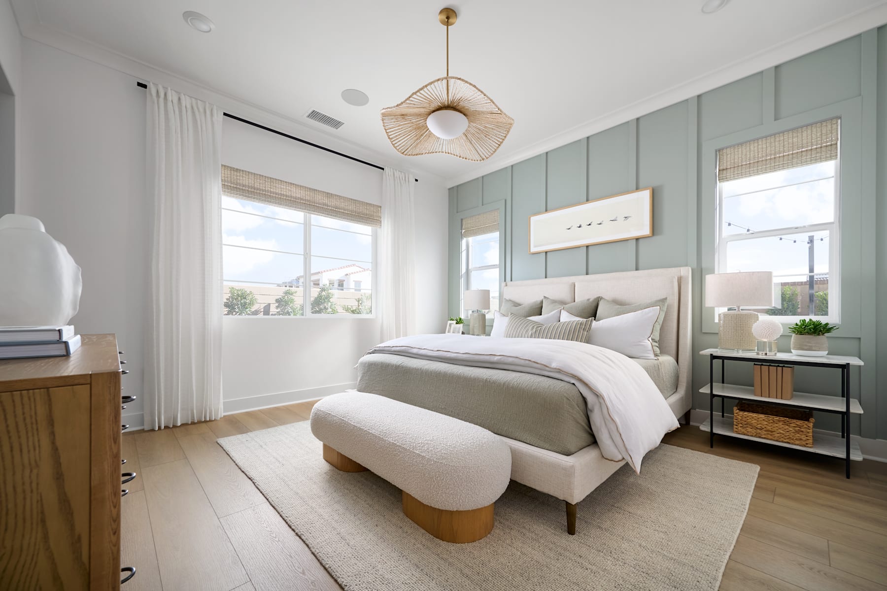 A cozy and inviting bedroom with a plush, neutral-toned bed, a woven pendant light, and a mix of natural and modern decor elements creating a serene and harmonious atmosphere.