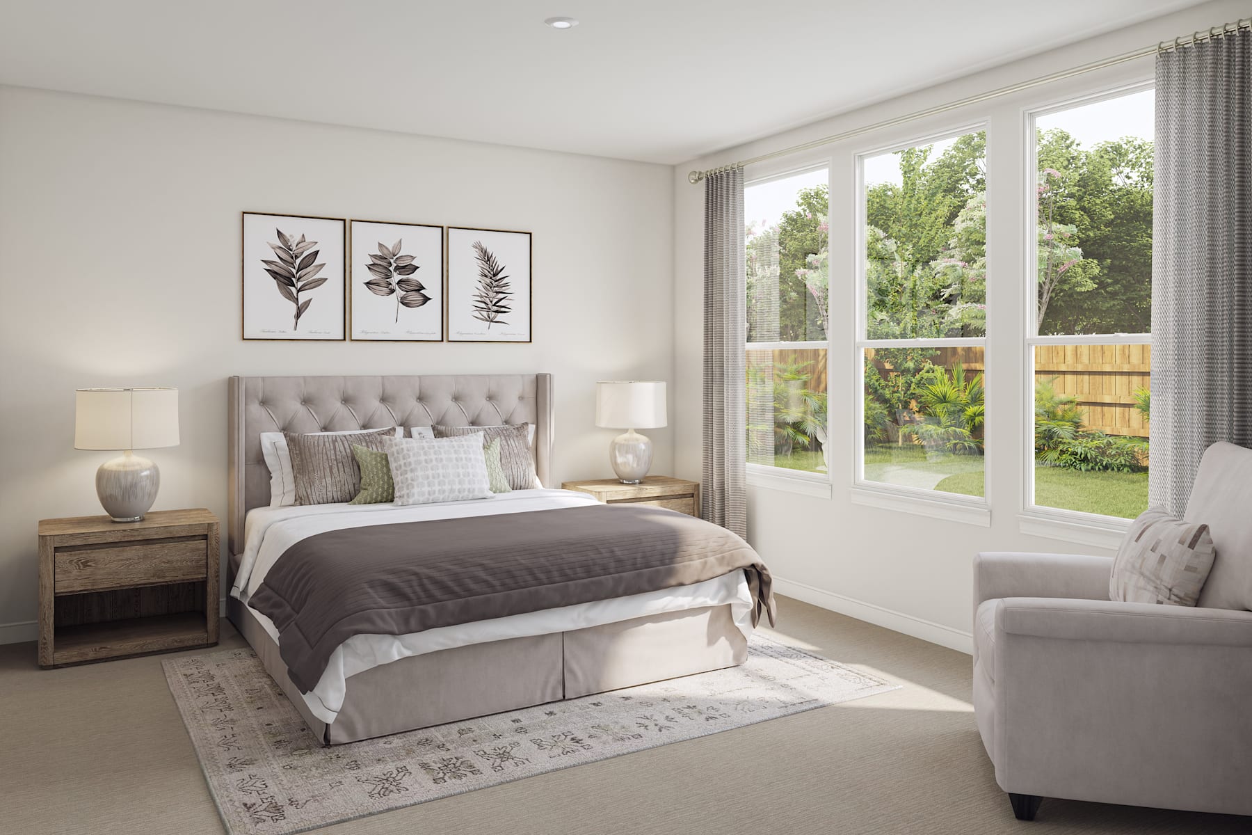 A cozy and well-appointed bedroom with a plush gray upholstered bed, framed botanical prints on the wall, and large windows overlooking a lush outdoor landscape.